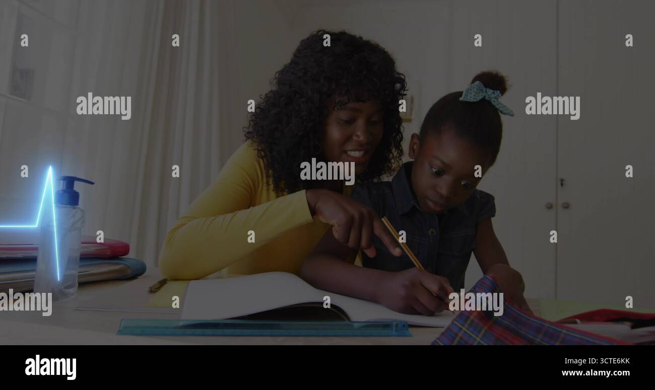 Madre pendente in alto giallo che punta al libro degli esercizi mentre la figlia scrive al punto di studio, con la matita Foto Stock