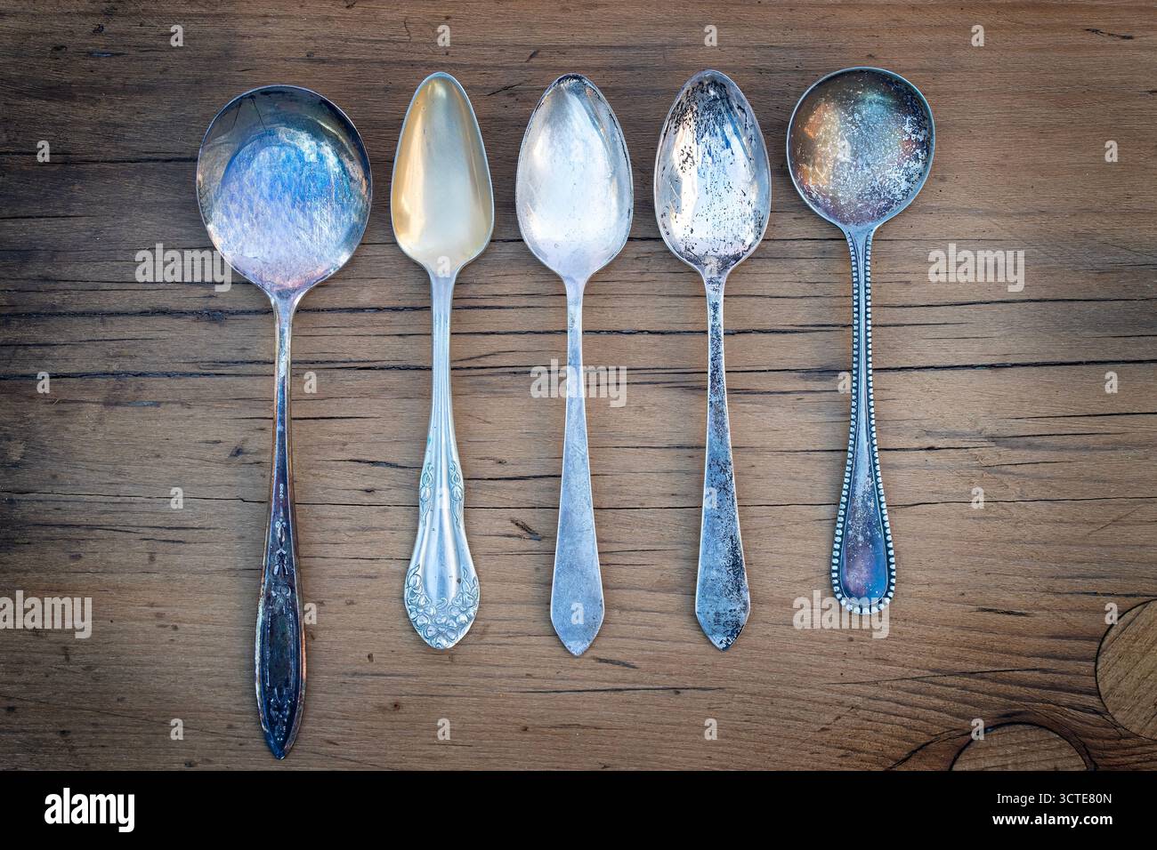 Varietà di cucchiai d'argento antichi su un tavolo della vecchia fattoria Foto Stock