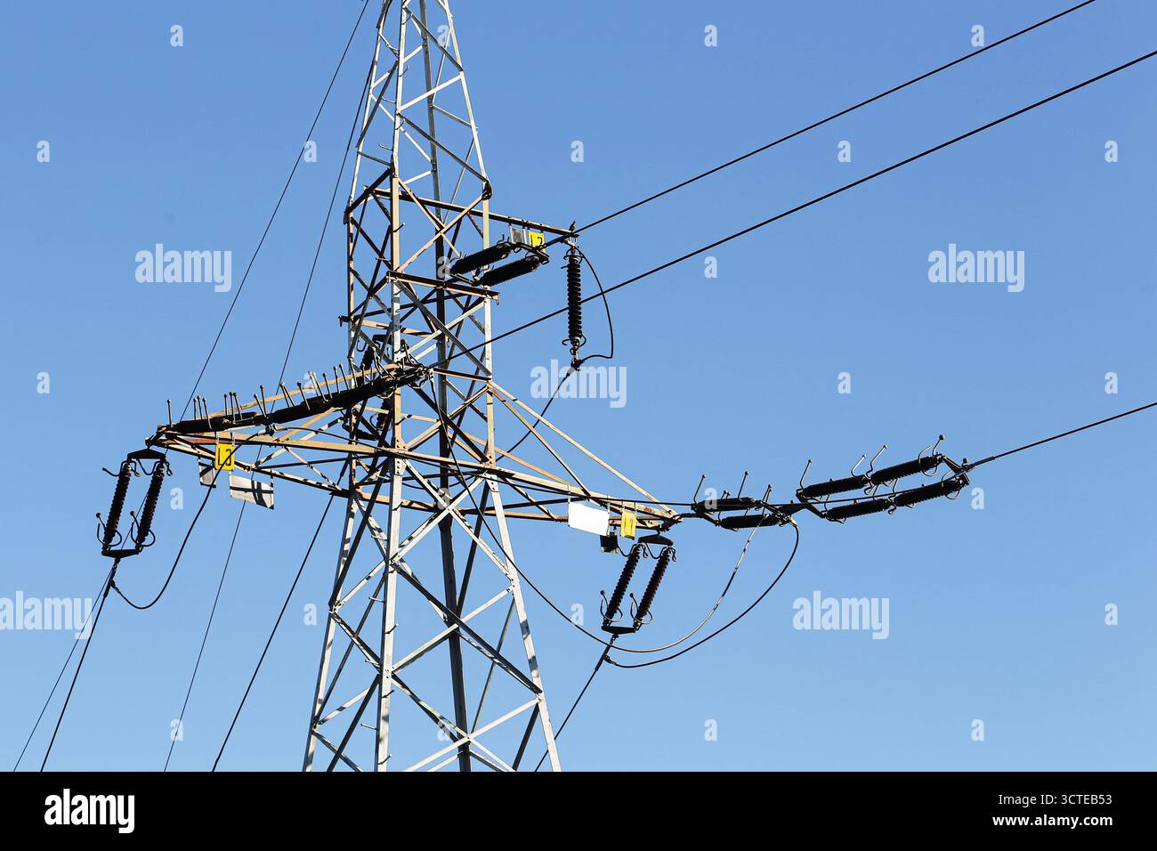 Torre di trasmissione dell'elettricità con cavi di alimentazione contro il cielo blu. Struttura ad alta tensione per il concetto di fornitura di energia e infrastruttura industriale. Foto Stock