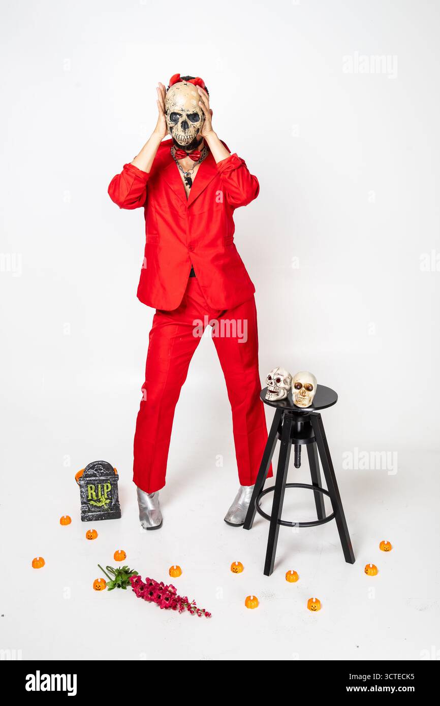 modello vestito con una tuta rossa che tiene un teschio davanti al viso Foto Stock
