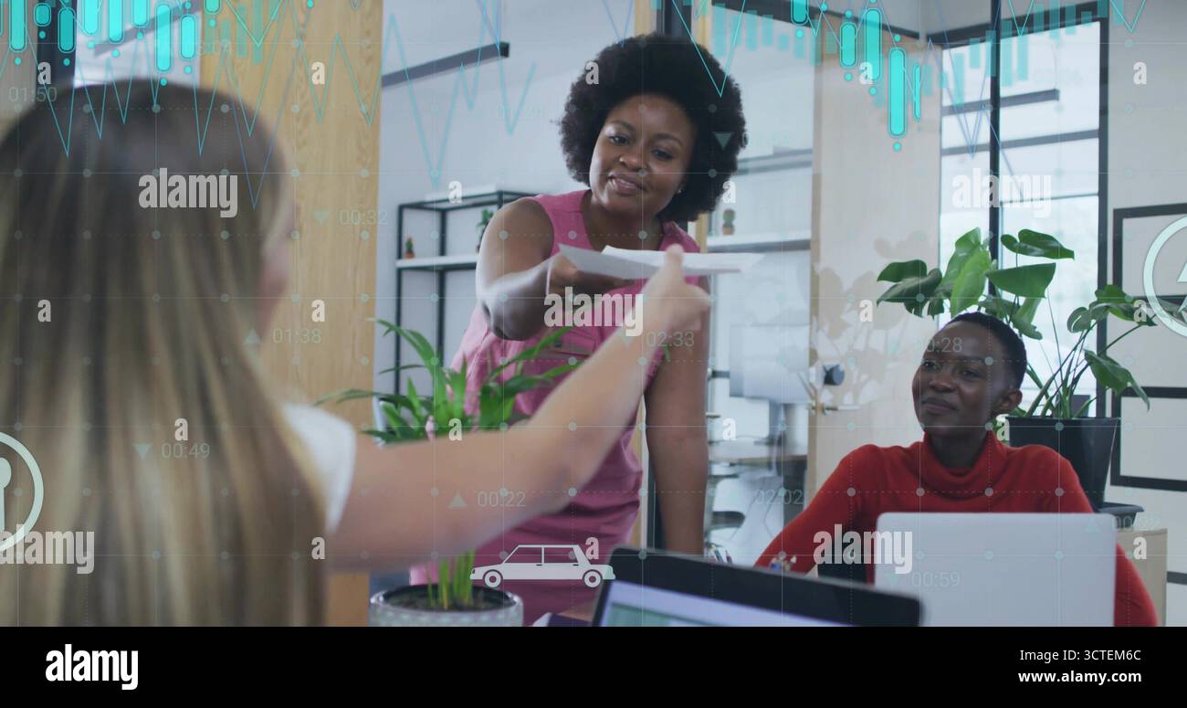 Donna africana pendente in abito rosa che riceve un foglio di carta in un ufficio collaborativo con un computer portatile Foto Stock