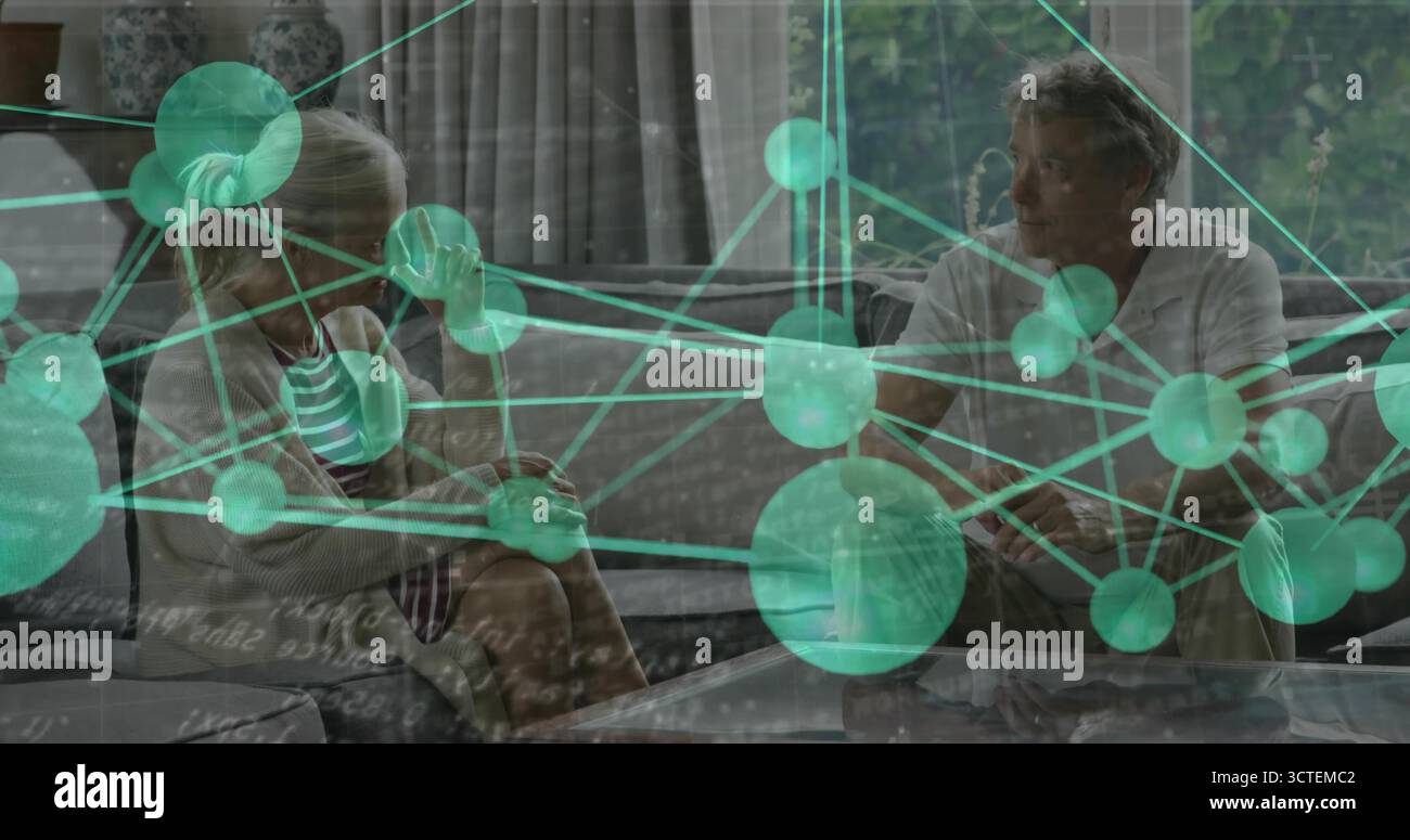 Due persone sedute che conversano su un divano grigio con tavolino da caffè nel soggiorno, con copertura della rete Foto Stock