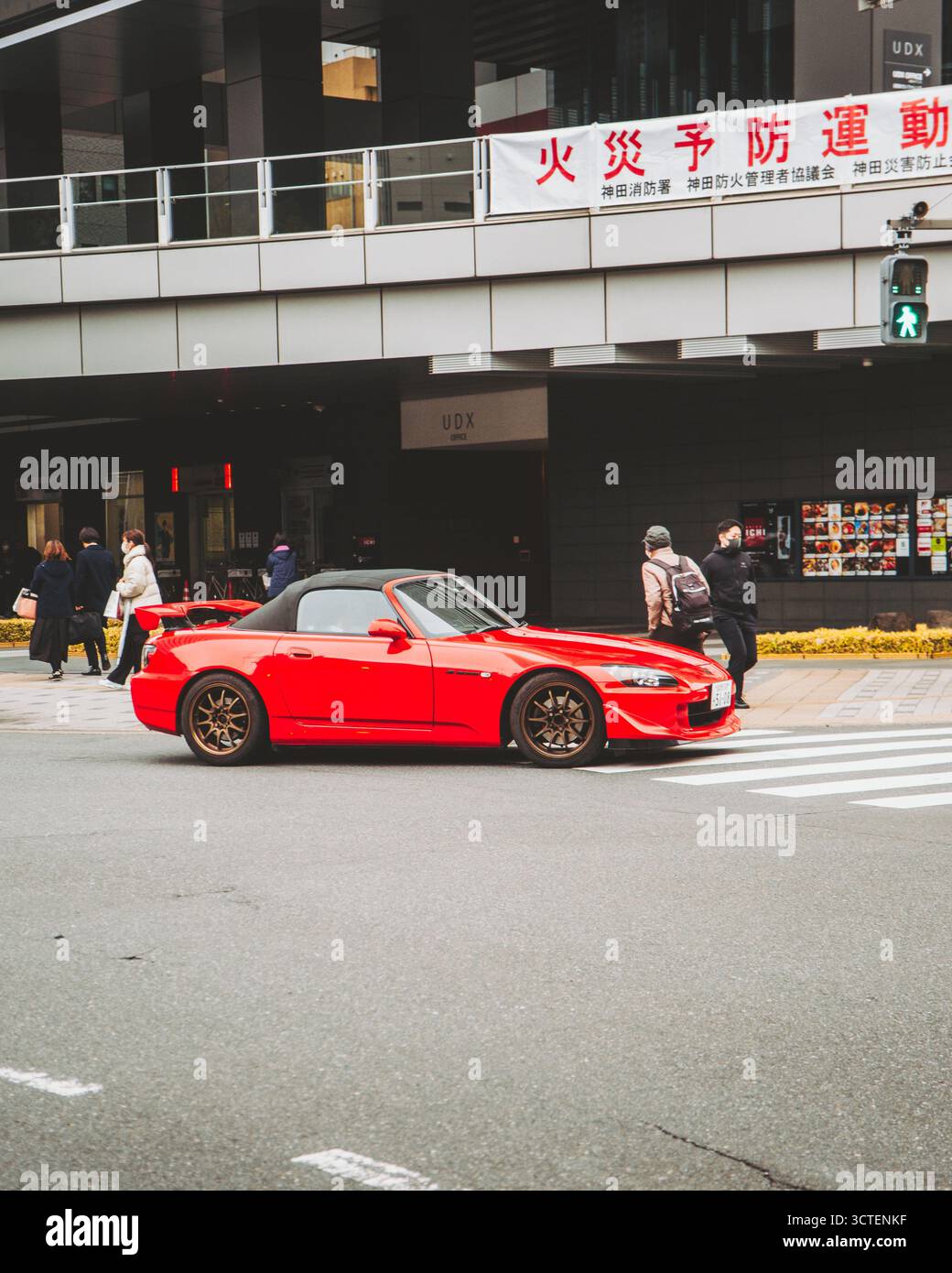 Akihabara, Giappone - 06 marzo 2025: Vista di una vibrante auto sportiva rossa posizionata ad un passaggio pedonale sullo sfondo di un edificio moderno. Foto Stock