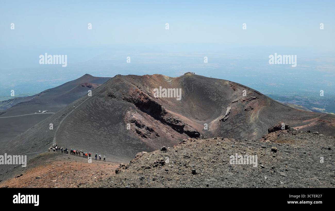 Un gruppo di escursionisti segue un percorso lungo il bordo di un vasto cratere vulcanico dormiente sull'Etna in Sicilia, Italia. Foto Stock