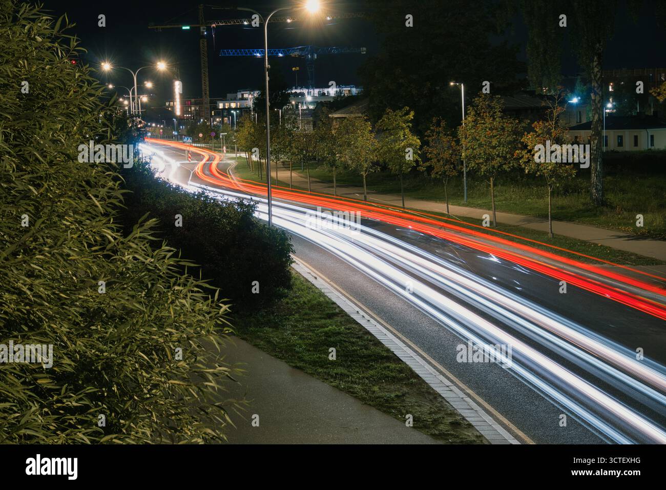 Percorsi notturni al semaforo sulla strada urbana curva Foto Stock