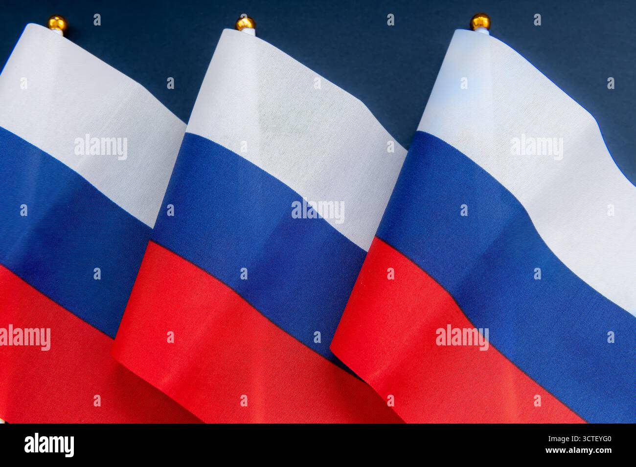 Una fila di bandiera della Federazione Russa su pali di bandiera isolati in blu scuro. Foto Stock