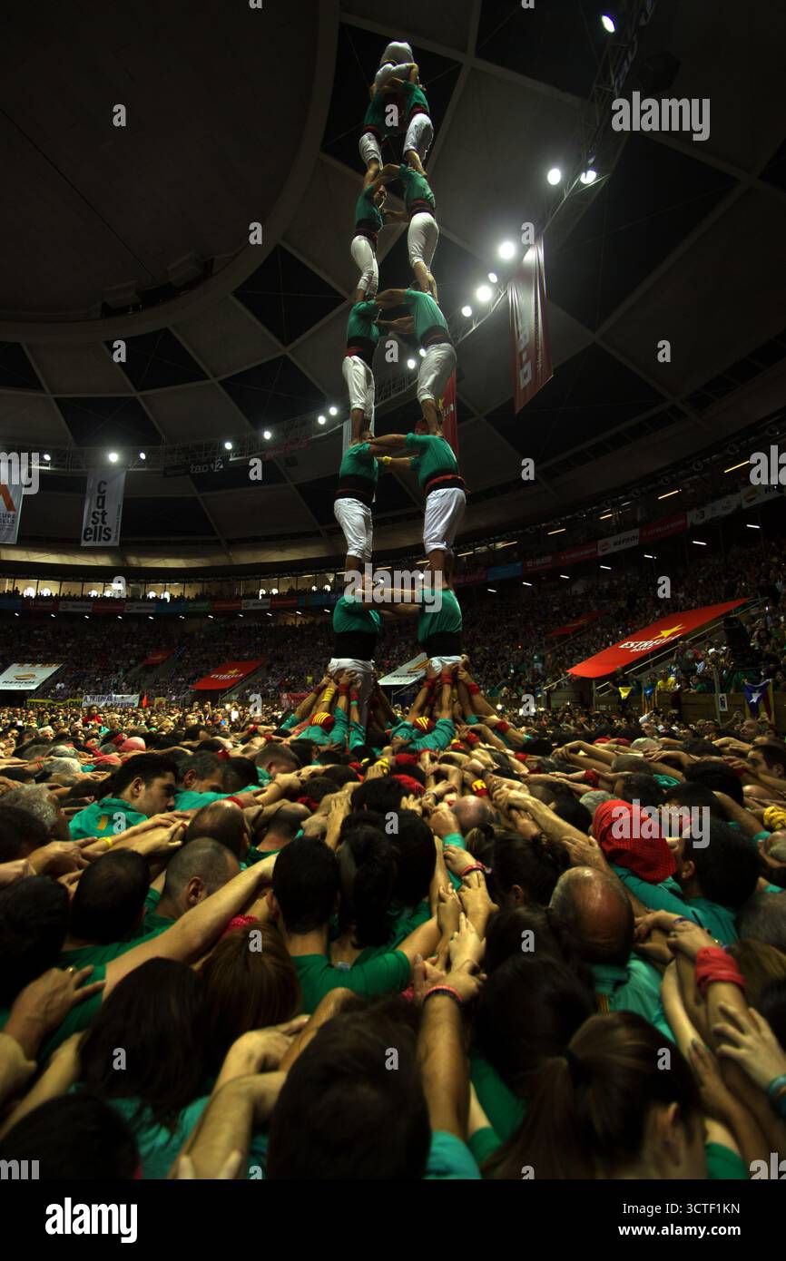 Tarragona, Spagna - 07 ottobre 2018: Vista di un imponente castello umano, i "Castellers", sorge con vivaci camicie verdi e un mare di mani che si avvicinano sullo sfondo di un'arena affollata. Foto Stock
