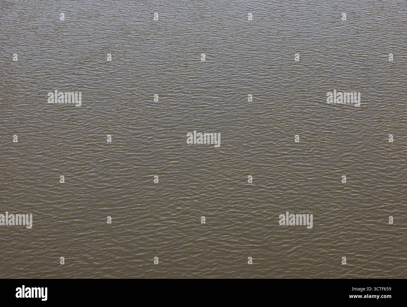 Increspature sull'acqua del lago. La luce del sole si riflette nell'acqua. Il sole splende accanto al lago. Sfondo delle onde oceaniche. Struttura ondulata del laghetto. Flusso d'acqua disordinato. Foto Stock