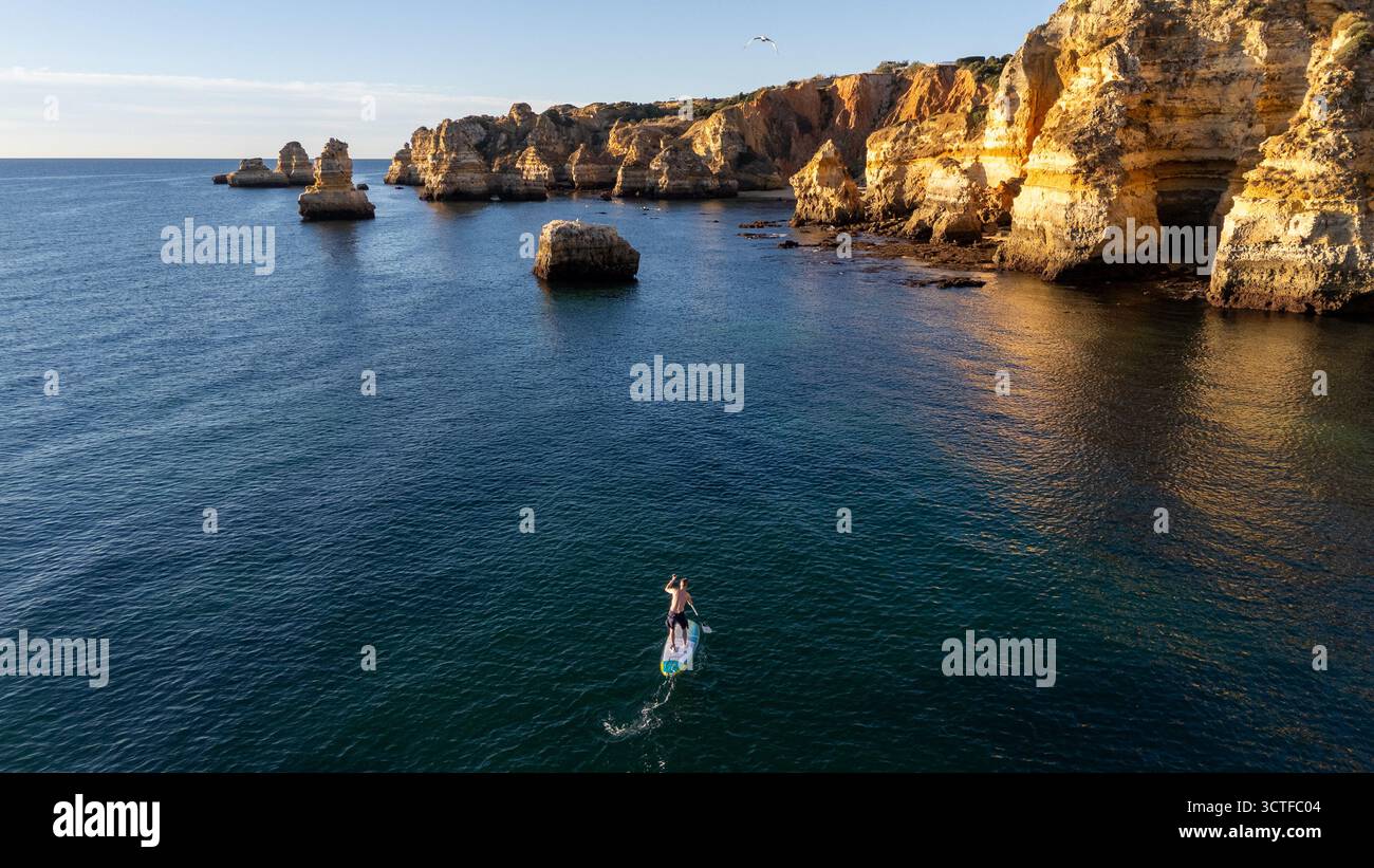 Portogallo, Algarve. Scogliere e oceano, vista aerea dall'alto verso il basso delle persone che fanno pagaia Foto Stock