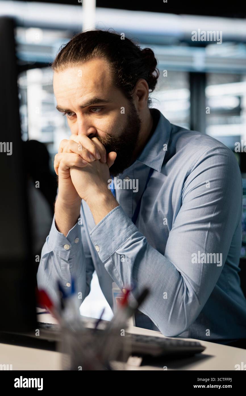 Il tecnico nella sala server si è preoccupato dopo aver letto un rapporto diagnostico che mostra un malfunzionamento critico dell'hardware sul PC. Ingegnere turbato dalle notifiche di errore che rischiano la stabilità della rete e l'uptime del sistema Foto Stock