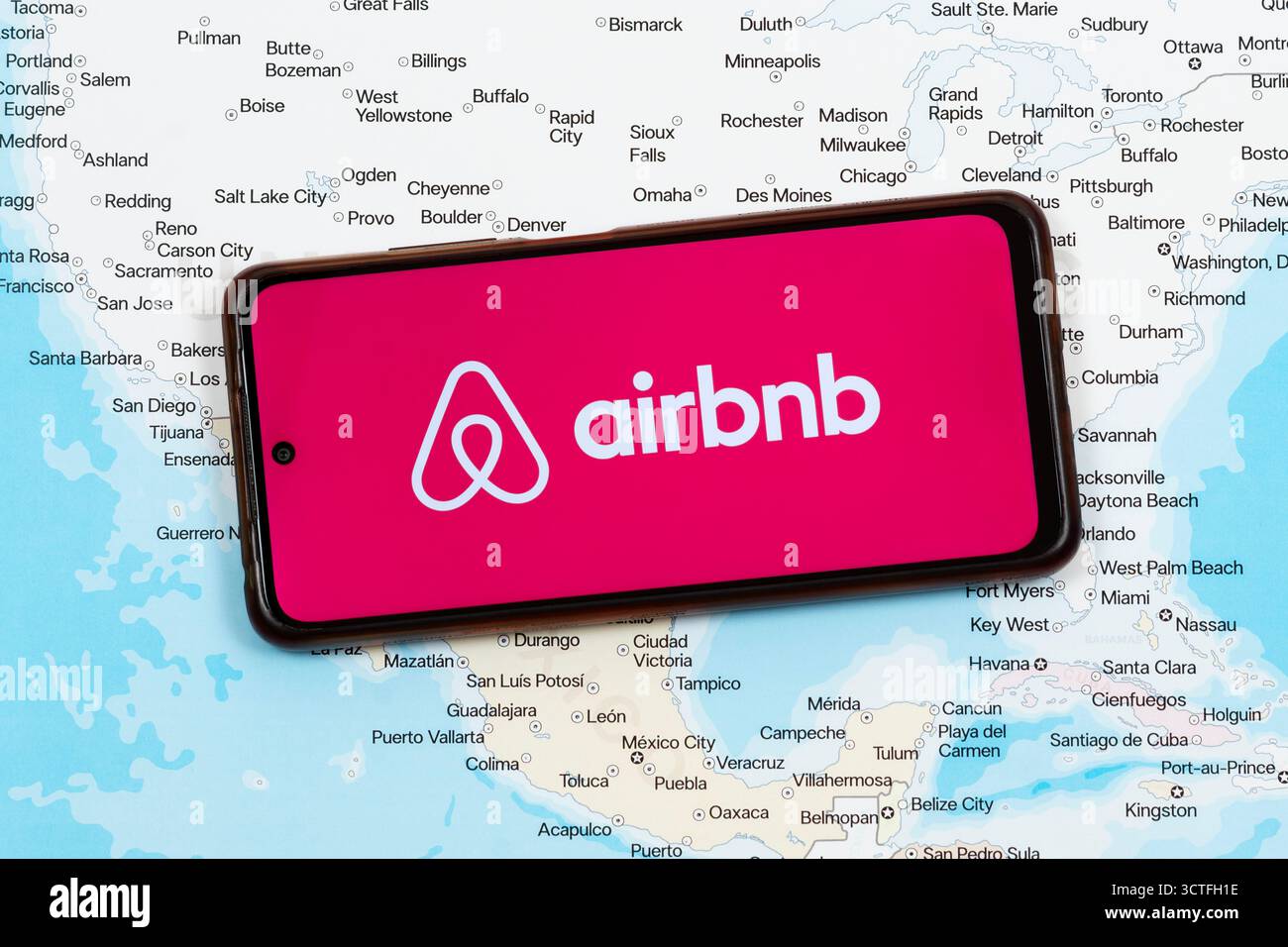 Primo piano di uno smartphone con logo airbnb rosa e bianco sopra una mappa politica del messico e degli stati uniti Foto Stock