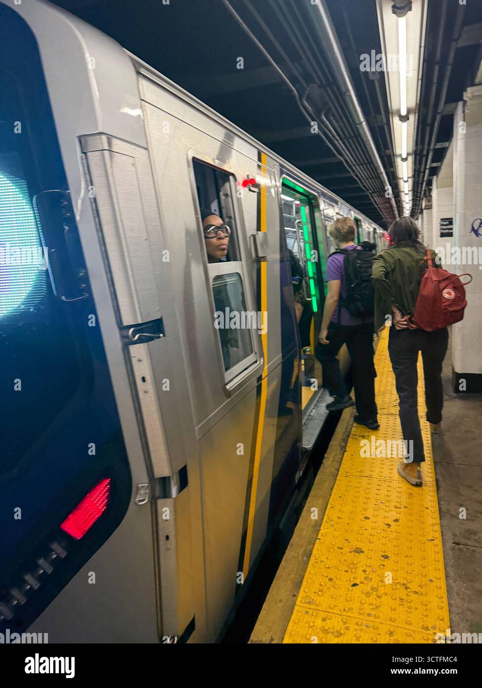 L'operatore del treno osserva la piattaforma mentre i passeggeri salgono a bordo di un treno della metropolitana la mattina a Brooklyn, New York. Foto Stock