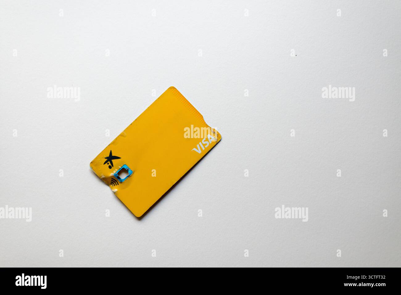 Carta di credito Visa gialla con chip rotto, isolata su sfondo bianco, simbolo di un metodo di pagamento danneggiato, difficoltà finanziarie e consumatore moderno Foto Stock
