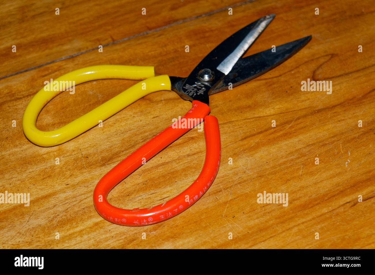 Forbici in stile cinese con classici manici ad anello su un piano in legno. Maniglie con coperture per tubi in plastica. Foto Stock
