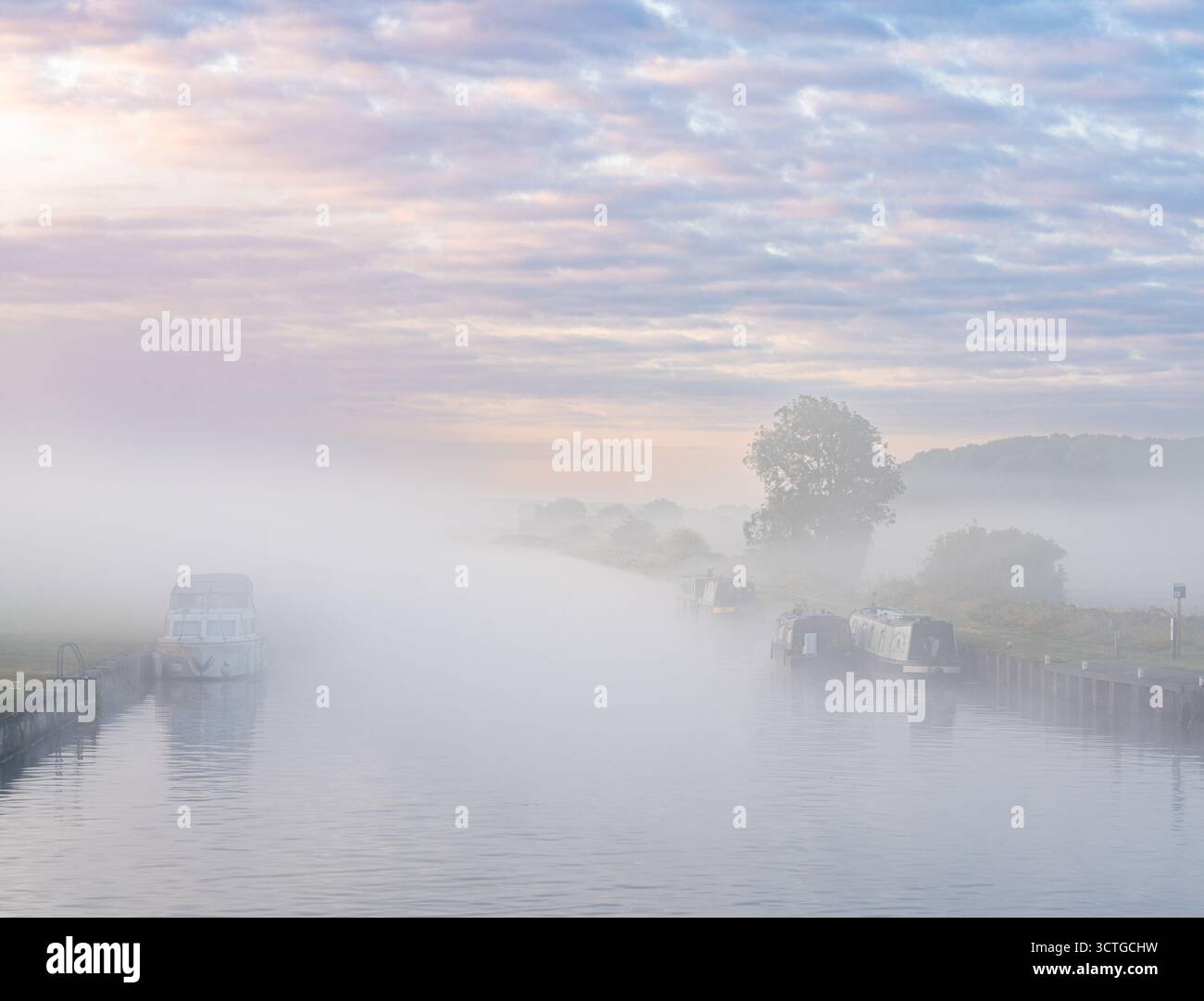 Le barche del canale ormeggiate nella nebbia mattutina all'alba Foto Stock