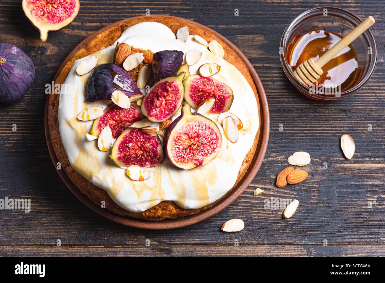 Torta di mandorle con fichi, panna montata e miele su sfondo di legno scuro, spazio copia. Ricetta per dolci di stagione per le vacanze autunnali. Foto Stock