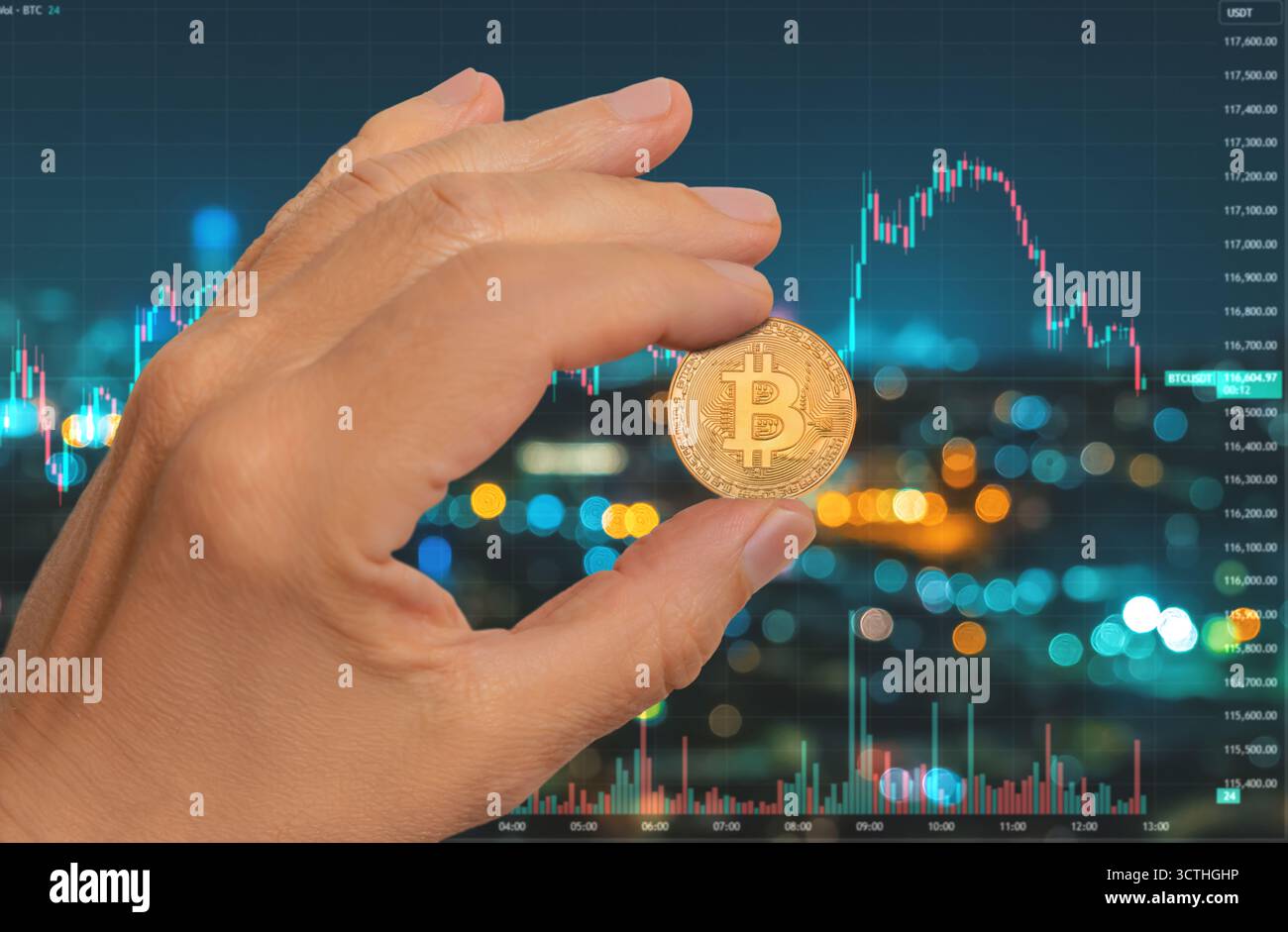 Una persona tiene in mano una brillante bitcoin fino a un display digitale che mostra i movimenti dei prezzi e le luci della città di notte in un ambiente urbano. Foto Stock