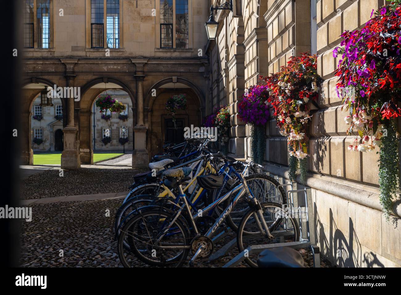 Cortile del Peterhouse College, Cambridge, con biciclette, archi in pietra e cesti di fiori appesi nel più antico college universitario d'Inghilterra Foto Stock