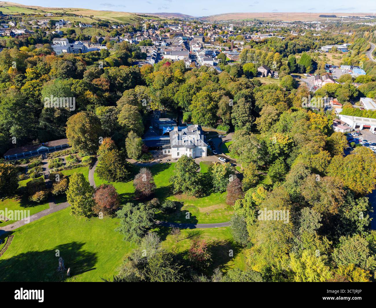 Tredegar, Galles - 10-06-2025: Fogliame autunnale che circonda Bedwellty House con la città di Tredegar sullo sfondo Foto Stock