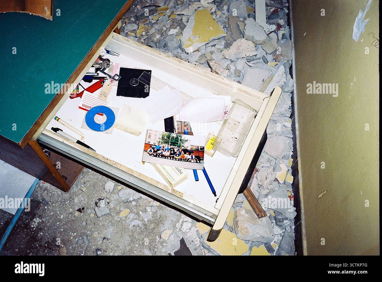 Il cassetto aperto in un ufficio abbandonato mostra una vecchia foto a colori tra i detriti, catturata su pellicola. Foto Stock