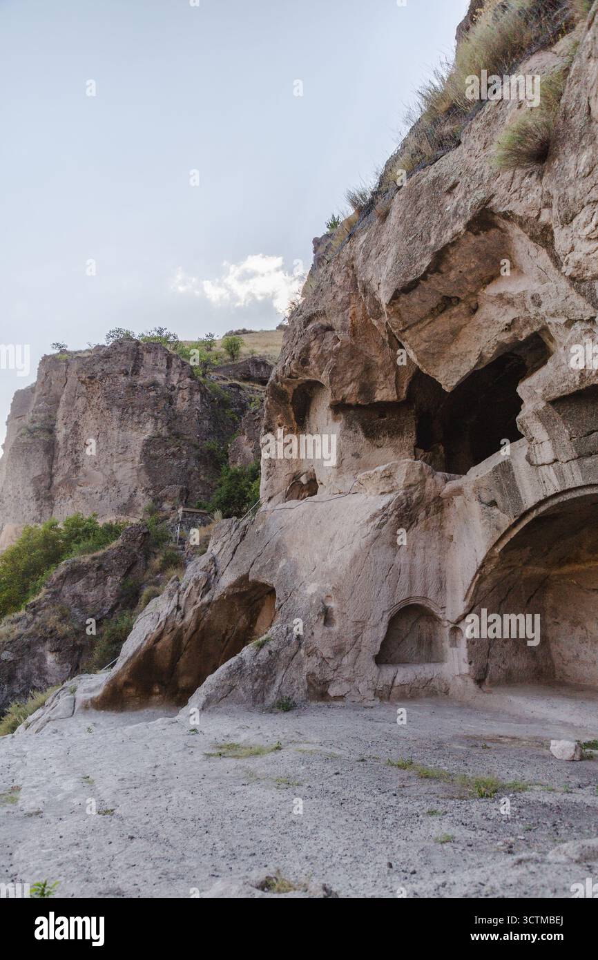 La vista delle formazioni rocciose scolpite, delle grotte e dell'architettura in pietra si fonde con l'aspro paesaggio sotto un cielo morbido, Vardzia, Imereti, Georgia. Foto Stock