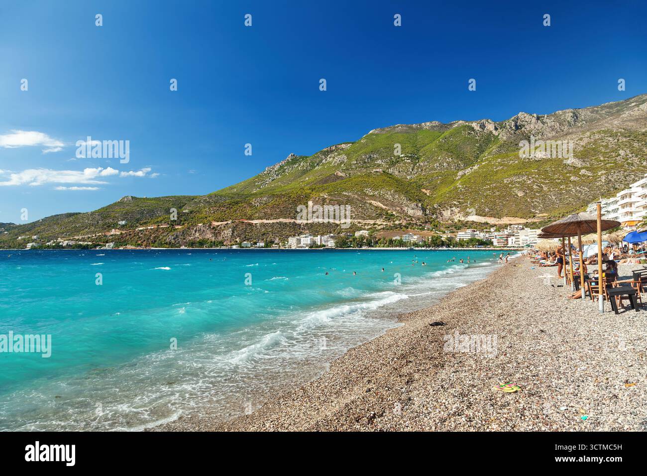Gente che si gode il sole e le acque turchesi sulla spiaggia di Loutraki, una popolare località turistica ad un'ora da Atene, Grecia. Foto Stock