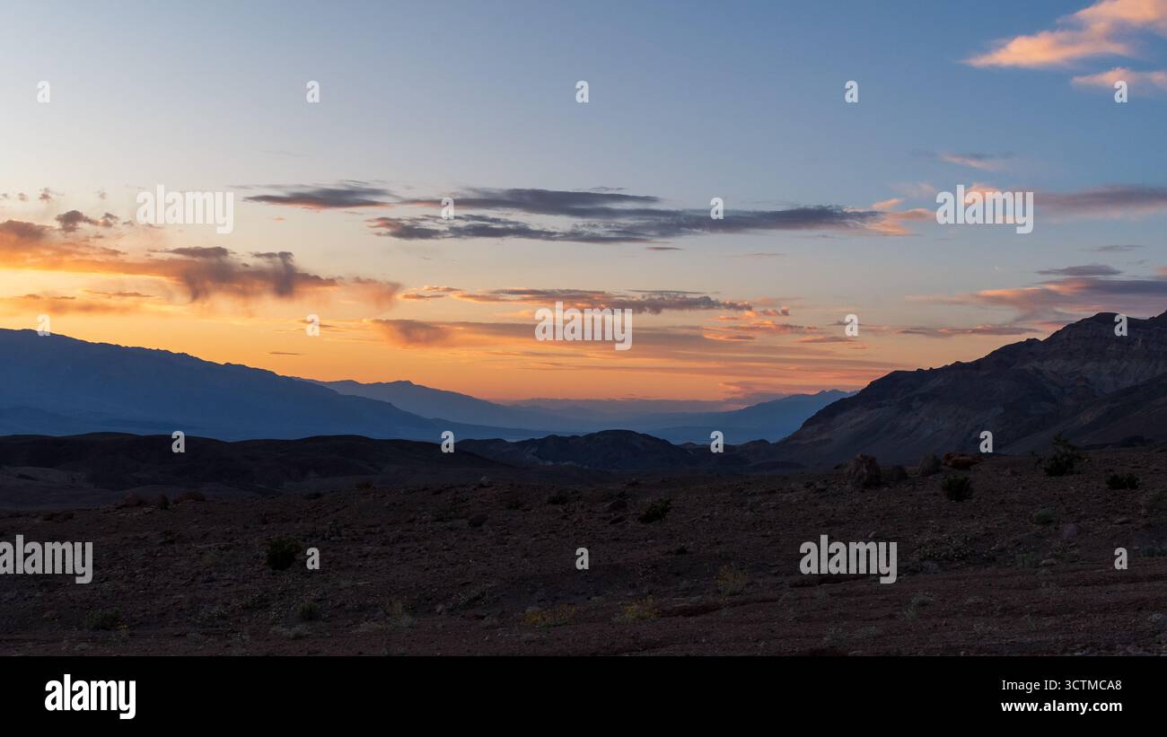 Il tramonto risplende sui crinali di montagna della Death Valley e sul terreno stratificato, una tranquilla scena desertica di dimensioni e calore. Foto Stock