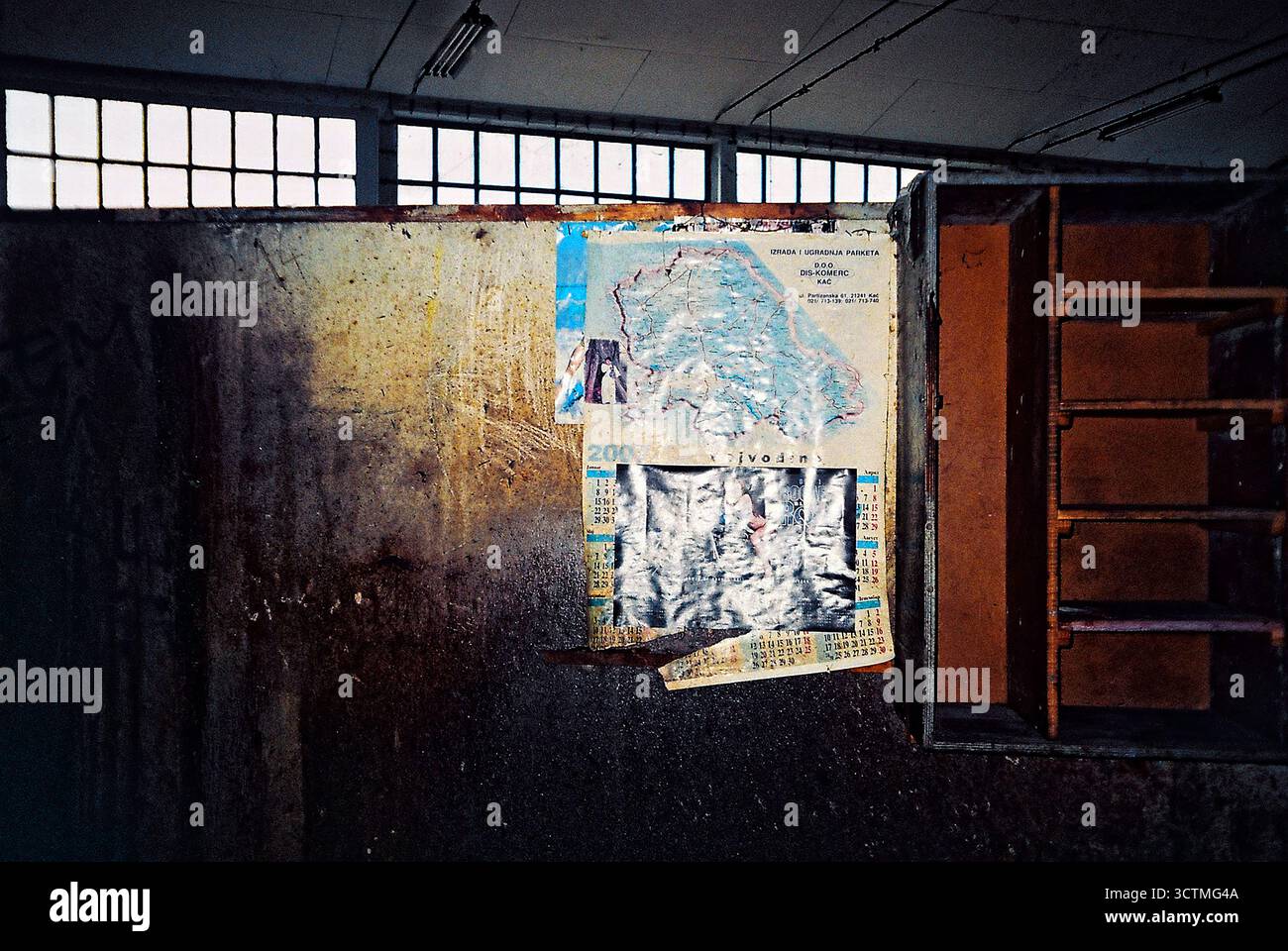 Vecchio calendario con una mappa della Vojvodina su una parete sporca e sporca in una fabbrica demolita, flash analogico con vignetta. Foto Stock