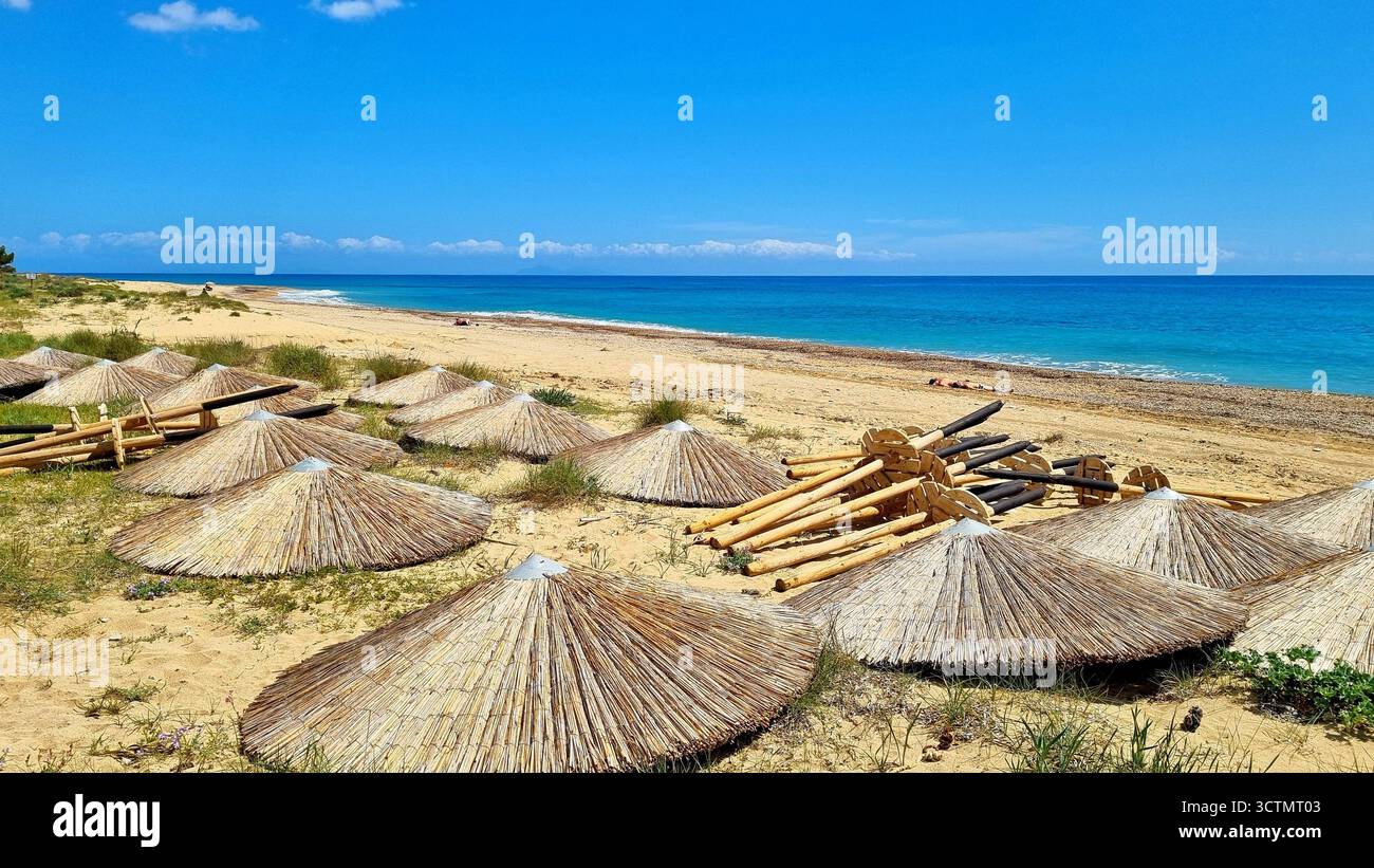 Paesaggio panoramico con mare turchese e ombrelloni di paglia sdraiati su una spiaggia sabbiosa a Cefalonia, Grecia Foto Stock