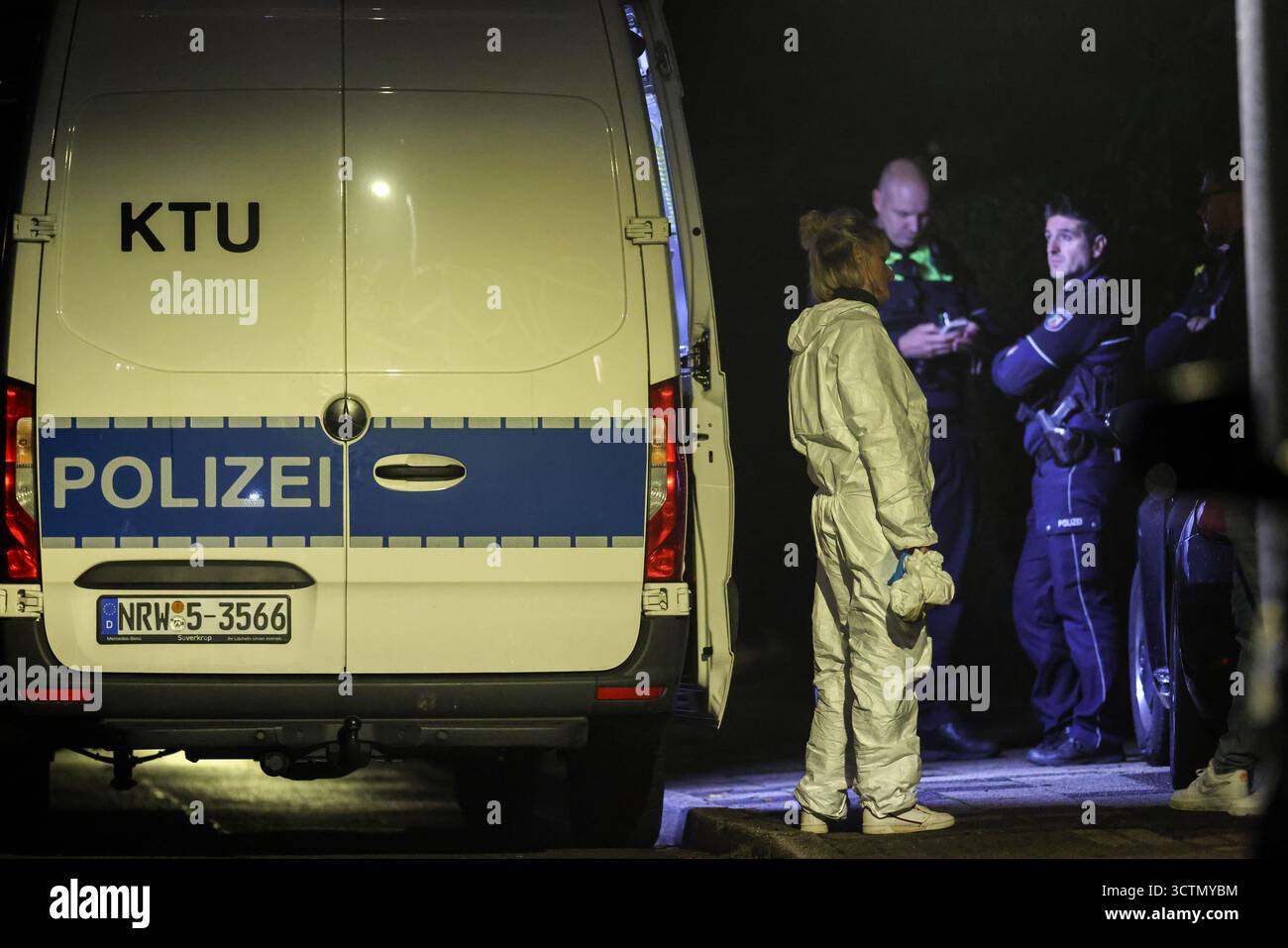 Herdecke, Germania. 7 ottobre 2025. Un ufficiale forense in una tuta forense si trova accanto al veicolo KTU (indagine forense), con agenti di polizia sullo sfondo. Crediti: Christoph Reichwein/dpa/Alamy Live News Foto Stock