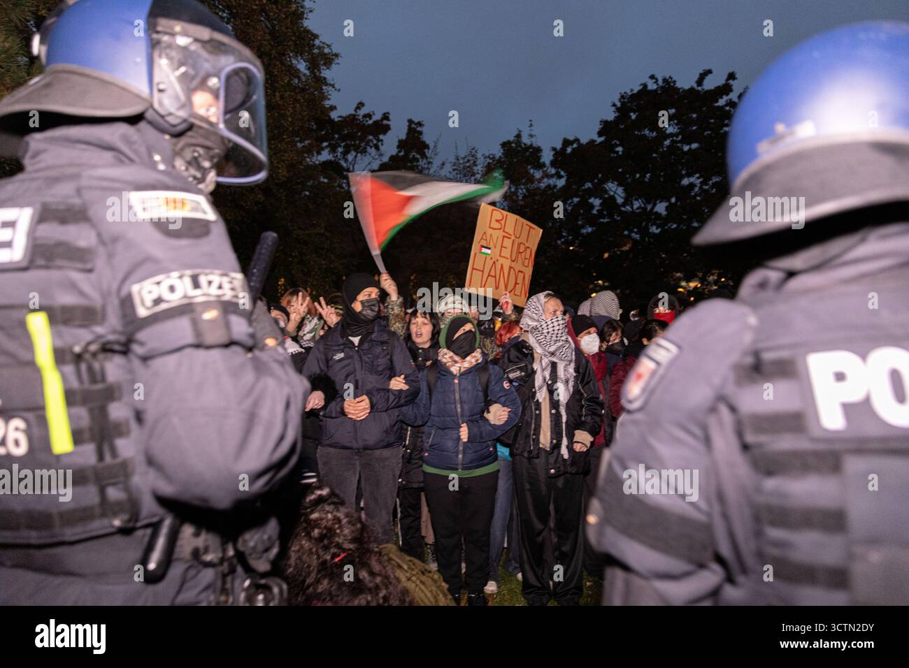 Centinaia di manifestanti filo-palestinesi si sono riuniti nei pressi della Fontana di Nettuno presso Alexanderplatz nel centro di Berlino martedì 7 ottobre 2025, nonostante il divieto della polizia alla manifestazione, in occasione del secondo anniversario degli attacchi terroristici di Hamas contro Israele. I partecipanti hanno cantato slogan come "Gloria alla resistenza", "Intifada fino alla vittoria" e "dal fiume al mare, la Palestina sarà libera”. Gli scontri scoppiarono quando gli ufficiali si trasferirono per disperdere il raduno, portando a numerosi arresti e scontri. La scena è diventata tesa e caotica mentre i manifestanti resistevano agli ordini della polizia. Il momento del rally o Foto Stock Centinaia di manifestanti filo-palestinesi si sono riuniti nei pressi della Fontana di Nettuno presso Alexanderplatz nel centro di Berlino martedì 7 ottobre 2025, nonostante il divieto della polizia alla manifestazione, in occasione del secondo anniversario degli attacchi terroristici di Hamas contro Israele. I partecipanti hanno cantato slogan come "Gloria alla resistenza", "Intifada fino alla vittoria" e "dal fiume al mare, la Palestina sarà libera”. Gli scontri scoppiarono quando gli ufficiali si trasferirono per disperdere il raduno, portando a numerosi arresti e scontri. La scena è diventata tesa e caotica mentre i manifestanti resistevano agli ordini della polizia. Il momento del rally o Foto Stock