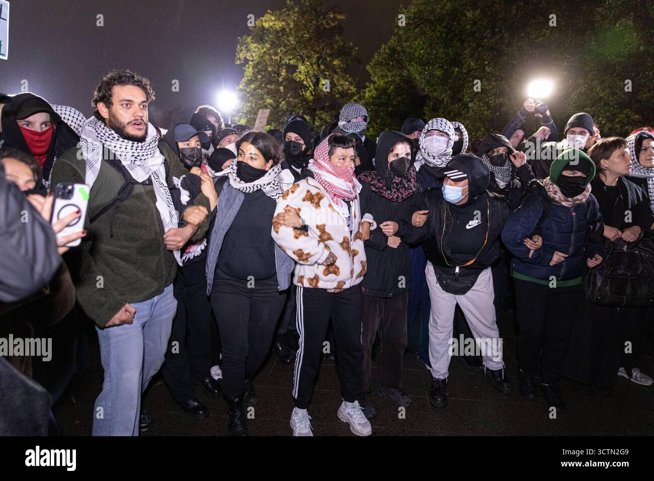 Centinaia di manifestanti filo-palestinesi si sono riuniti nei pressi della Fontana di Nettuno presso Alexanderplatz nel centro di Berlino martedì 7 ottobre 2025, nonostante il divieto della polizia alla manifestazione, in occasione del secondo anniversario degli attacchi terroristici di Hamas contro Israele. I partecipanti hanno cantato slogan come "Gloria alla resistenza", "Intifada fino alla vittoria" e "dal fiume al mare, la Palestina sarà libera”. Gli scontri scoppiarono quando gli ufficiali si trasferirono per disperdere il raduno, portando a numerosi arresti e scontri. La scena è diventata tesa e caotica mentre i manifestanti resistevano agli ordini della polizia. Il momento del rally o Foto Stock Centinaia di manifestanti filo-palestinesi si sono riuniti nei pressi della Fontana di Nettuno presso Alexanderplatz nel centro di Berlino martedì 7 ottobre 2025, nonostante il divieto della polizia alla manifestazione, in occasione del secondo anniversario degli attacchi terroristici di Hamas contro Israele. I partecipanti hanno cantato slogan come "Gloria alla resistenza", "Intifada fino alla vittoria" e "dal fiume al mare, la Palestina sarà libera”. Gli scontri scoppiarono quando gli ufficiali si trasferirono per disperdere il raduno, portando a numerosi arresti e scontri. La scena è diventata tesa e caotica mentre i manifestanti resistevano agli ordini della polizia. Il momento del rally o Foto Stock