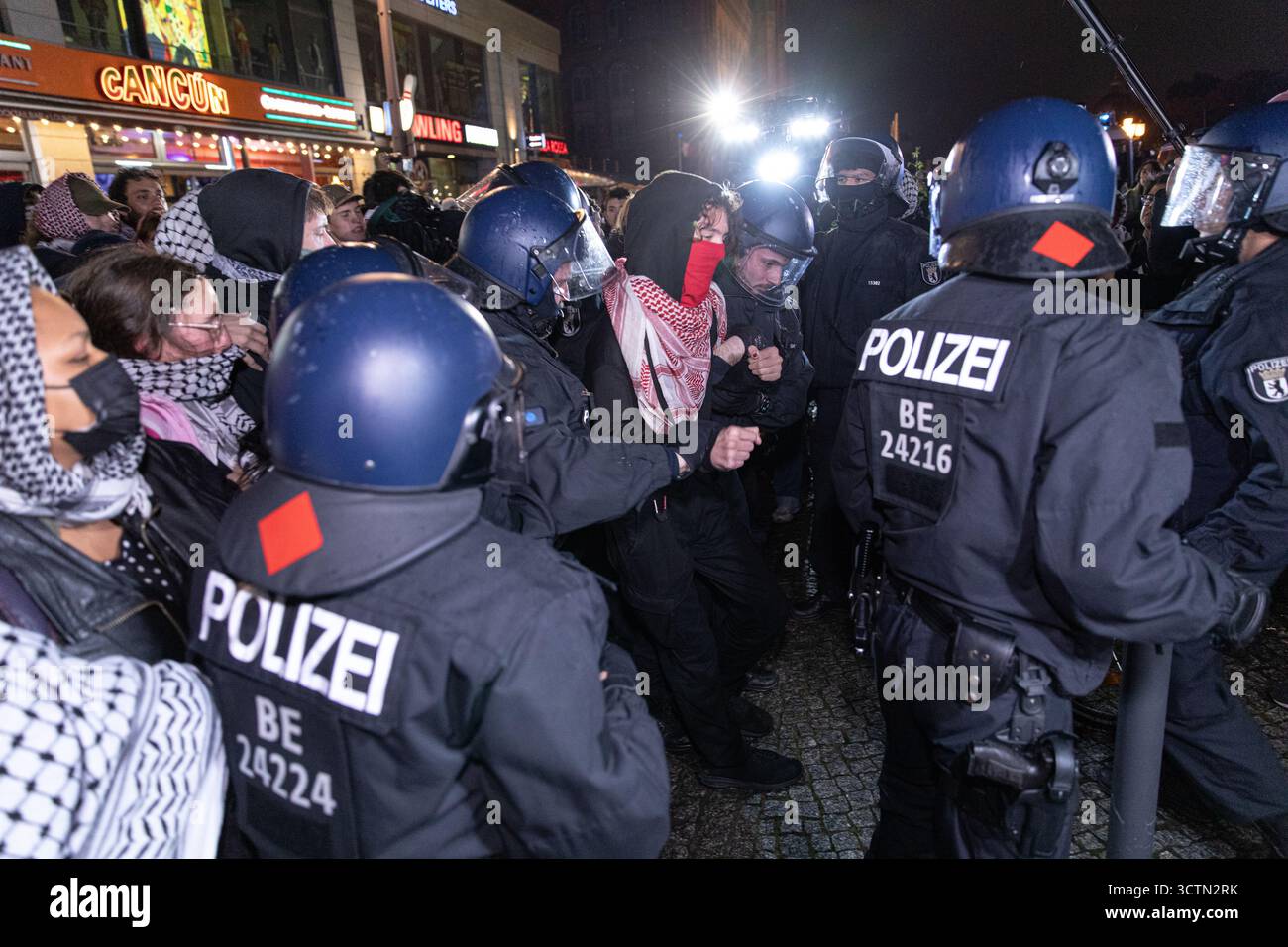 Centinaia di manifestanti filo-palestinesi si sono riuniti nei pressi della Fontana di Nettuno presso Alexanderplatz nel centro di Berlino martedì 7 ottobre 2025, nonostante il divieto della polizia alla manifestazione, in occasione del secondo anniversario degli attacchi terroristici di Hamas contro Israele. I partecipanti hanno cantato slogan come "Gloria alla resistenza", "Intifada fino alla vittoria" e "dal fiume al mare, la Palestina sarà libera”. Gli scontri scoppiarono quando gli ufficiali si trasferirono per disperdere il raduno, portando a numerosi arresti e scontri. La scena è diventata tesa e caotica mentre i manifestanti resistevano agli ordini della polizia. Il momento del rally o Foto Stock Centinaia di manifestanti filo-palestinesi si sono riuniti nei pressi della Fontana di Nettuno presso Alexanderplatz nel centro di Berlino martedì 7 ottobre 2025, nonostante il divieto della polizia alla manifestazione, in occasione del secondo anniversario degli attacchi terroristici di Hamas contro Israele. I partecipanti hanno cantato slogan come "Gloria alla resistenza", "Intifada fino alla vittoria" e "dal fiume al mare, la Palestina sarà libera”. Gli scontri scoppiarono quando gli ufficiali si trasferirono per disperdere il raduno, portando a numerosi arresti e scontri. La scena è diventata tesa e caotica mentre i manifestanti resistevano agli ordini della polizia. Il momento del rally o Foto Stock
