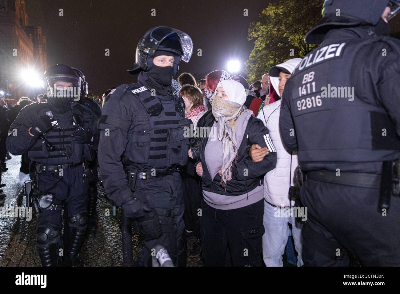 Centinaia di manifestanti filo-palestinesi si sono riuniti nei pressi della Fontana di Nettuno presso Alexanderplatz nel centro di Berlino martedì 7 ottobre 2025, nonostante il divieto della polizia alla manifestazione, in occasione del secondo anniversario degli attacchi terroristici di Hamas contro Israele. I partecipanti hanno cantato slogan come "Gloria alla resistenza", "Intifada fino alla vittoria" e "dal fiume al mare, la Palestina sarà libera”. Gli scontri scoppiarono quando gli ufficiali si trasferirono per disperdere il raduno, portando a numerosi arresti e scontri. La scena è diventata tesa e caotica mentre i manifestanti resistevano agli ordini della polizia. Il momento del rally o Foto Stock Centinaia di manifestanti filo-palestinesi si sono riuniti nei pressi della Fontana di Nettuno presso Alexanderplatz nel centro di Berlino martedì 7 ottobre 2025, nonostante il divieto della polizia alla manifestazione, in occasione del secondo anniversario degli attacchi terroristici di Hamas contro Israele. I partecipanti hanno cantato slogan come "Gloria alla resistenza", "Intifada fino alla vittoria" e "dal fiume al mare, la Palestina sarà libera”. Gli scontri scoppiarono quando gli ufficiali si trasferirono per disperdere il raduno, portando a numerosi arresti e scontri. La scena è diventata tesa e caotica mentre i manifestanti resistevano agli ordini della polizia. Il momento del rally o Foto Stock