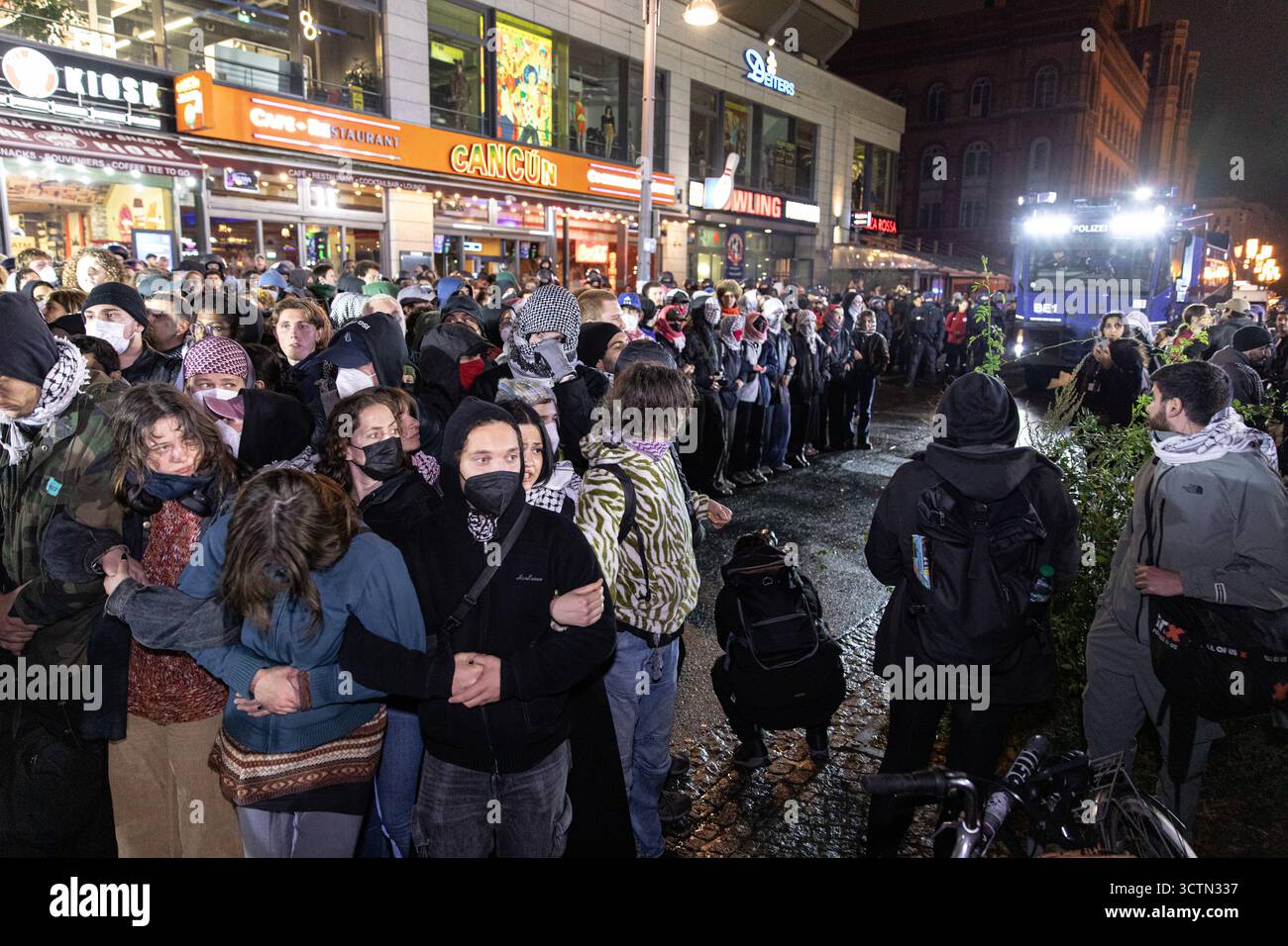Centinaia di manifestanti filo-palestinesi si sono riuniti nei pressi della Fontana di Nettuno presso Alexanderplatz nel centro di Berlino martedì 7 ottobre 2025, nonostante il divieto della polizia alla manifestazione, in occasione del secondo anniversario degli attacchi terroristici di Hamas contro Israele. I partecipanti hanno cantato slogan come "Gloria alla resistenza", "Intifada fino alla vittoria" e "dal fiume al mare, la Palestina sarà libera”. Gli scontri scoppiarono quando gli ufficiali si trasferirono per disperdere il raduno, portando a numerosi arresti e scontri. La scena è diventata tesa e caotica mentre i manifestanti resistevano agli ordini della polizia. Il momento del rally o Foto Stock Centinaia di manifestanti filo-palestinesi si sono riuniti nei pressi della Fontana di Nettuno presso Alexanderplatz nel centro di Berlino martedì 7 ottobre 2025, nonostante il divieto della polizia alla manifestazione, in occasione del secondo anniversario degli attacchi terroristici di Hamas contro Israele. I partecipanti hanno cantato slogan come "Gloria alla resistenza", "Intifada fino alla vittoria" e "dal fiume al mare, la Palestina sarà libera”. Gli scontri scoppiarono quando gli ufficiali si trasferirono per disperdere il raduno, portando a numerosi arresti e scontri. La scena è diventata tesa e caotica mentre i manifestanti resistevano agli ordini della polizia. Il momento del rally o Foto Stock