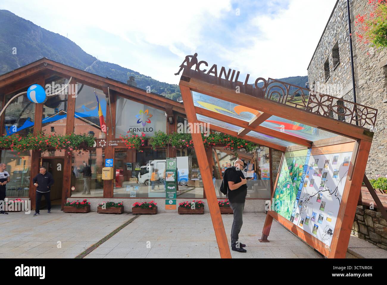 Un visitatore di sesso maschile che guarda la mappa dei sentieri escursionistici di montagna sul cartellone all'esterno dell'edificio dell'ufficio del turismo di Canillo. Canillo, Andorra Foto Stock
