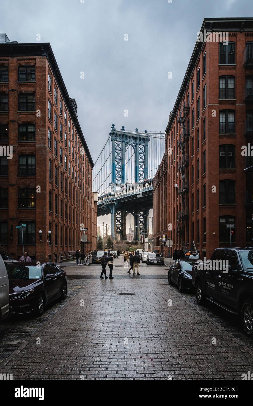 Vista sulla strada urbana con persone che camminano verso un ponte. Foto Stock