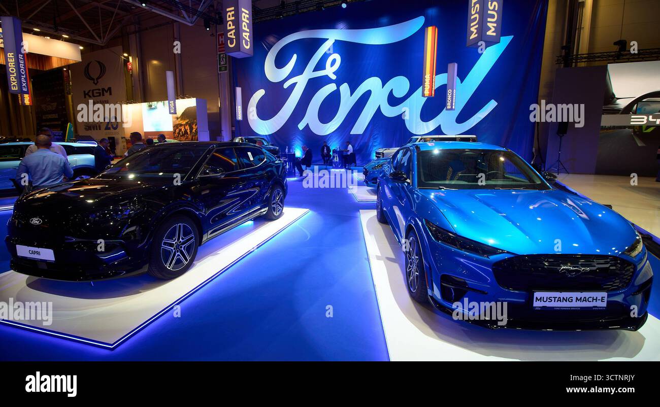 Bucarest, Romania. 7 ottobre 2025: Un SUV elettrico blu Ford Mustang Mach-e è in mostra vicino al nuovo SUV elettrico Ford Capri presso lo stand Ford durante l'Auto Show di Bucarest e gli accessori 2025. Crediti: Lucian Alecu/Alamy Live News Foto Stock