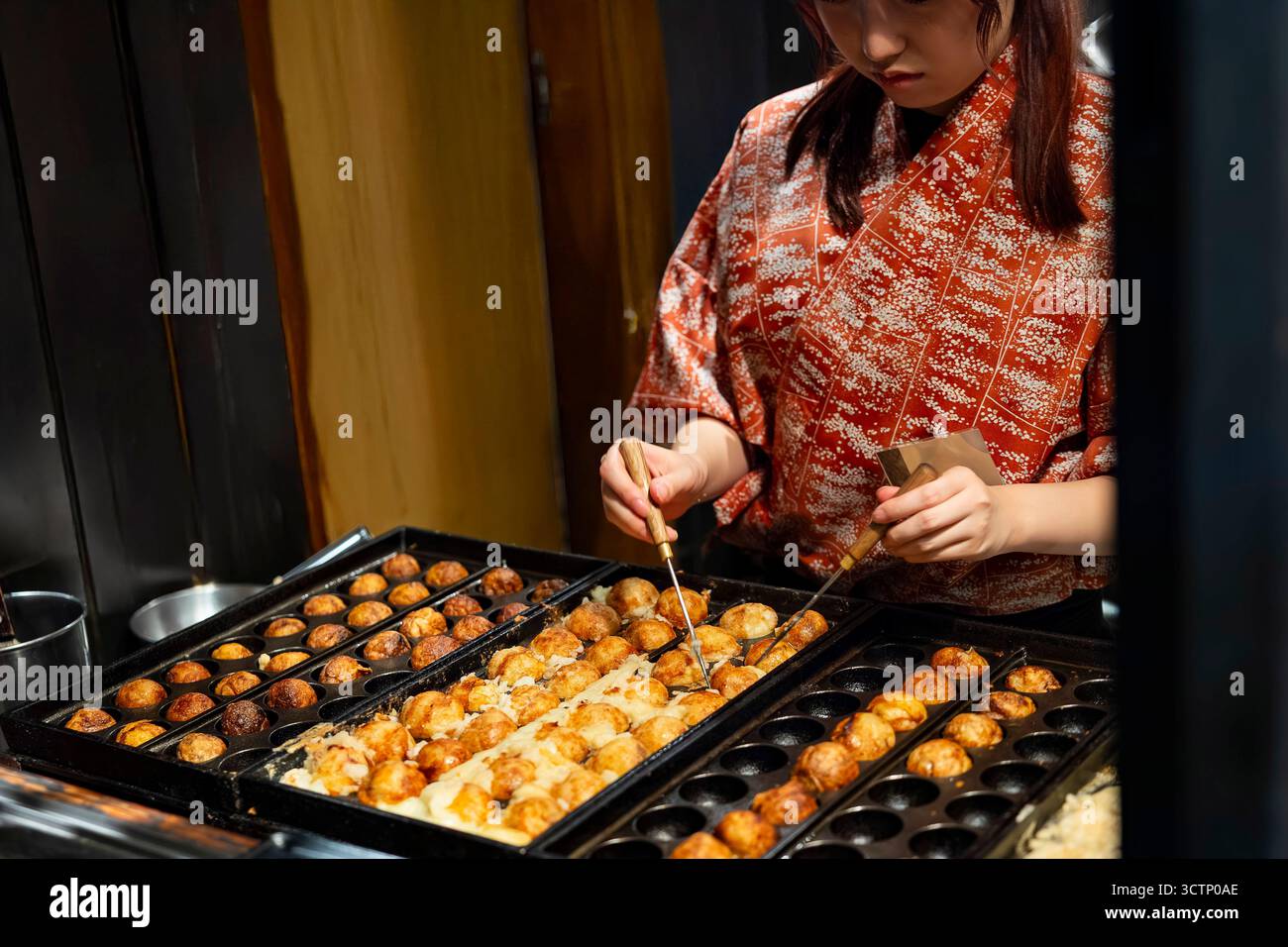 Donna giapponese che cucina il takoyaki, cibo di strada giapponese, Giappone Foto Stock
