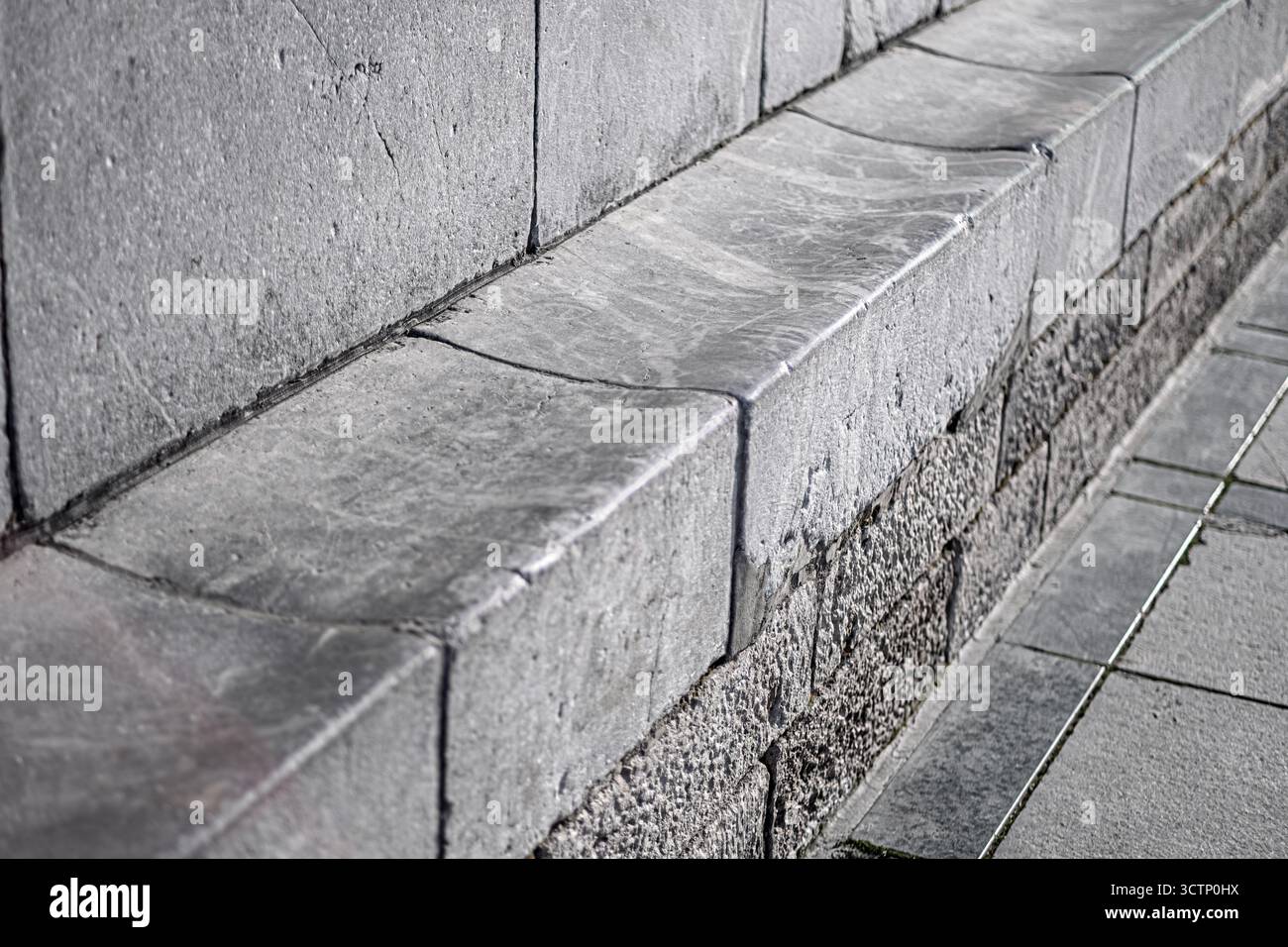 Immagine dettagliata di un bordo di banco in marmo o pietra. Mostra la consistenza e l'usura della superficie. Ideale per la progettazione, l'architettura o la pianificazione urbana Foto Stock