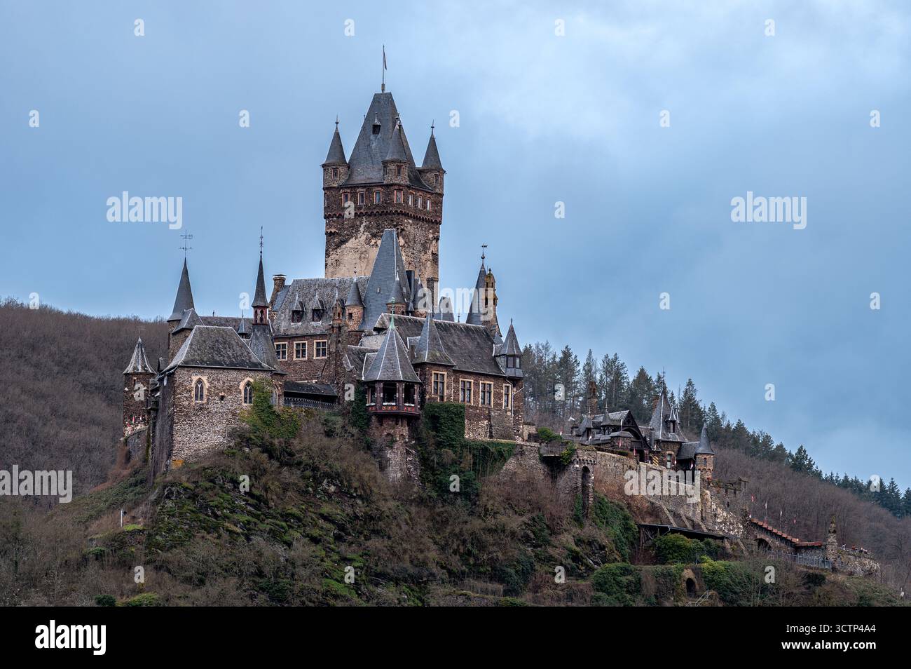 Ripresa a tutta larghezza del castello di Cochem, arroccato in cima a una collina, incorniciato contro un cielo mattutino nuvoloso, che mette in risalto l'architettura medievale Foto Stock