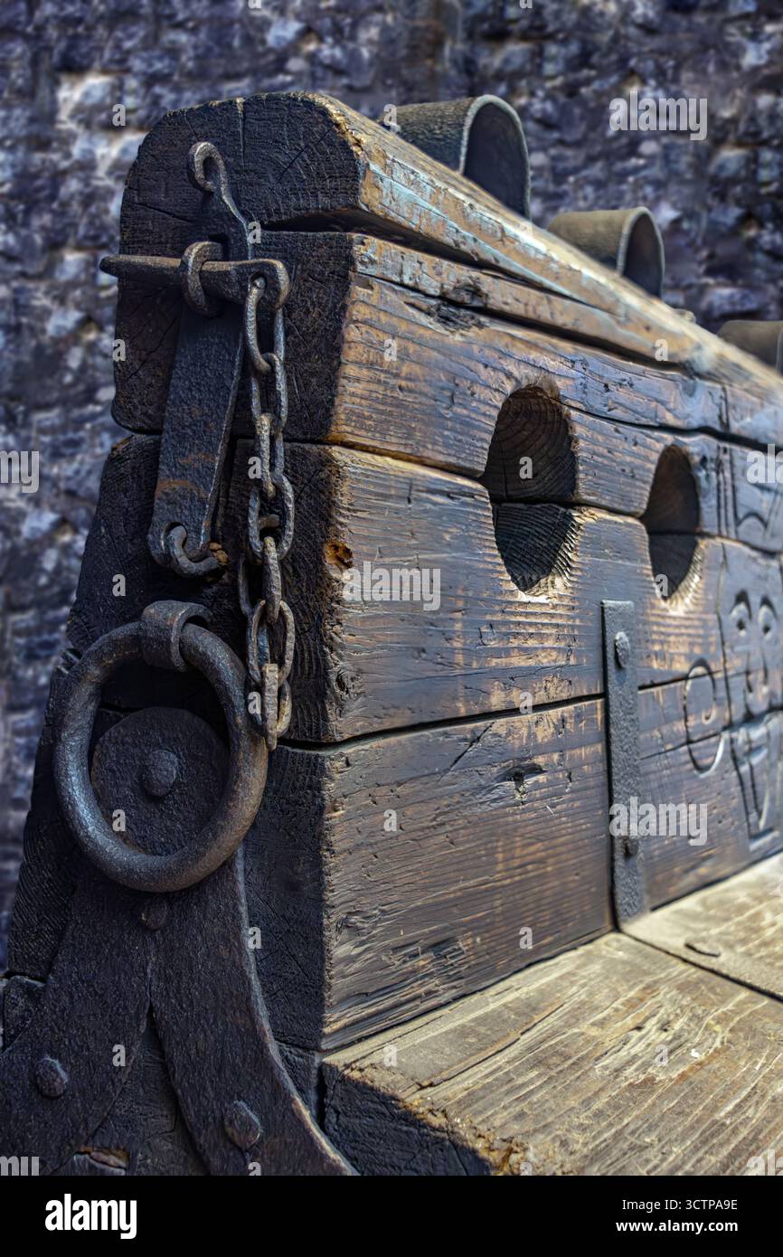 Vecchi tronchi ruvidi, vista ravvicinata, storico dispositivo di tortura per punizioni fisiche con manette di ferro e un buco per i piedi. Foto Stock