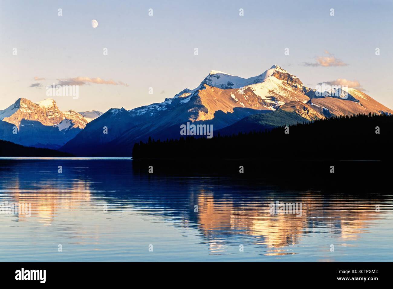 Vista panoramica su un lago di montagna nell'ora d'oro con la luna sul cielo Foto Stock