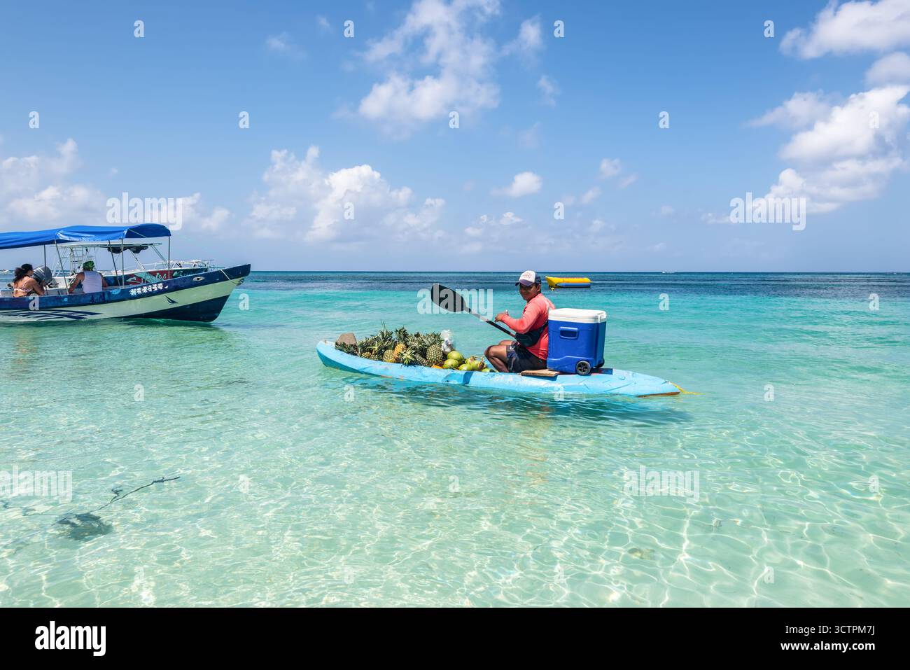 West Bay Beach, Roatan Island, Honduras - 16 aprile 2024: Vendita di noci di cocco e ananas da una barca a West Bay Beach a Roatan, Honduras. Foto Stock