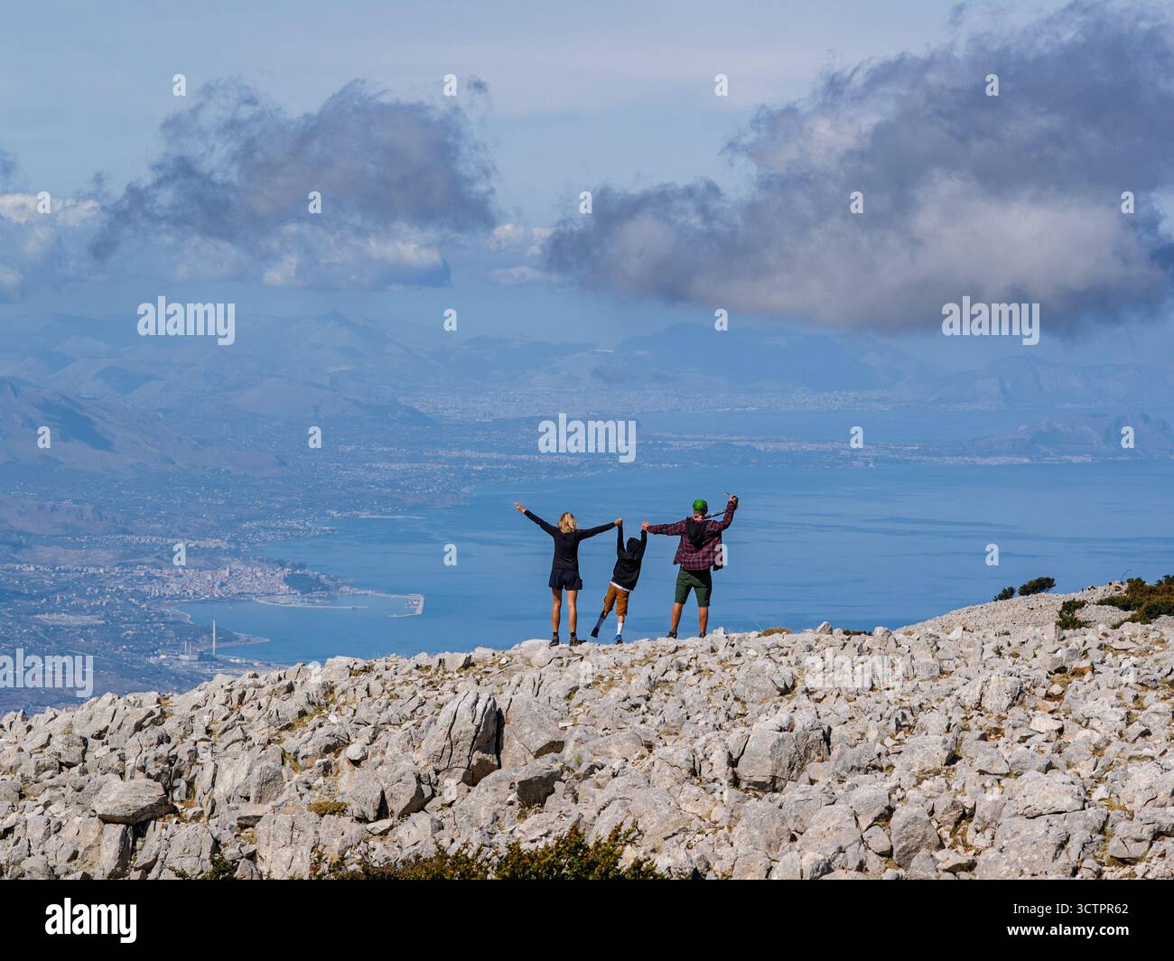Vista aerea di coppia, famiglia in piedi su una cima siciliana Carbonara con vedute panoramiche del Mar Tirreno, delle scogliere circostanti e del paesaggio lussureggiante Foto Stock