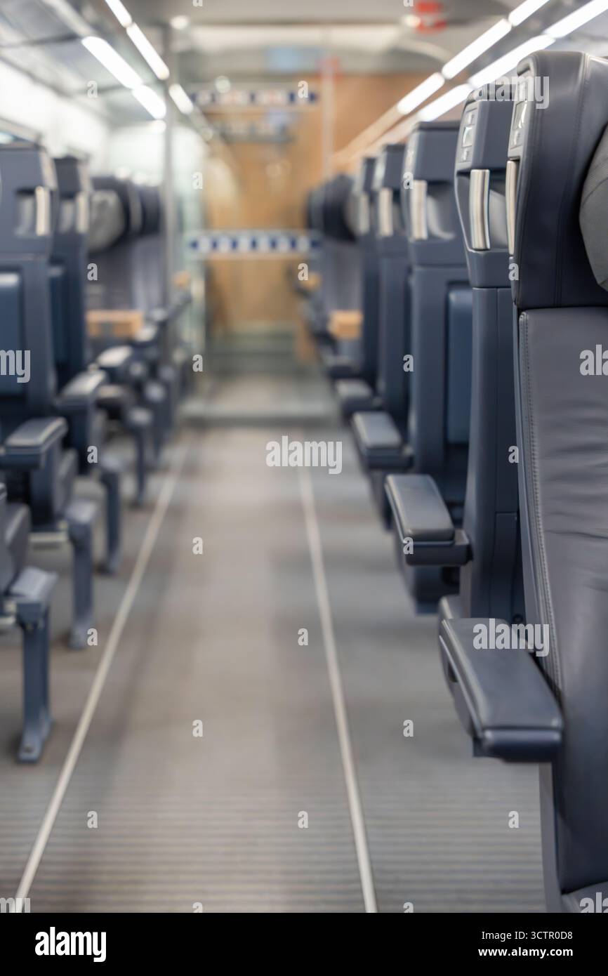 Corsia nel treno di prima classe con effetto sfondo sfocato. Concentrati sulla disposizione moderna dei posti a sedere e sul design pulito. Foto Stock