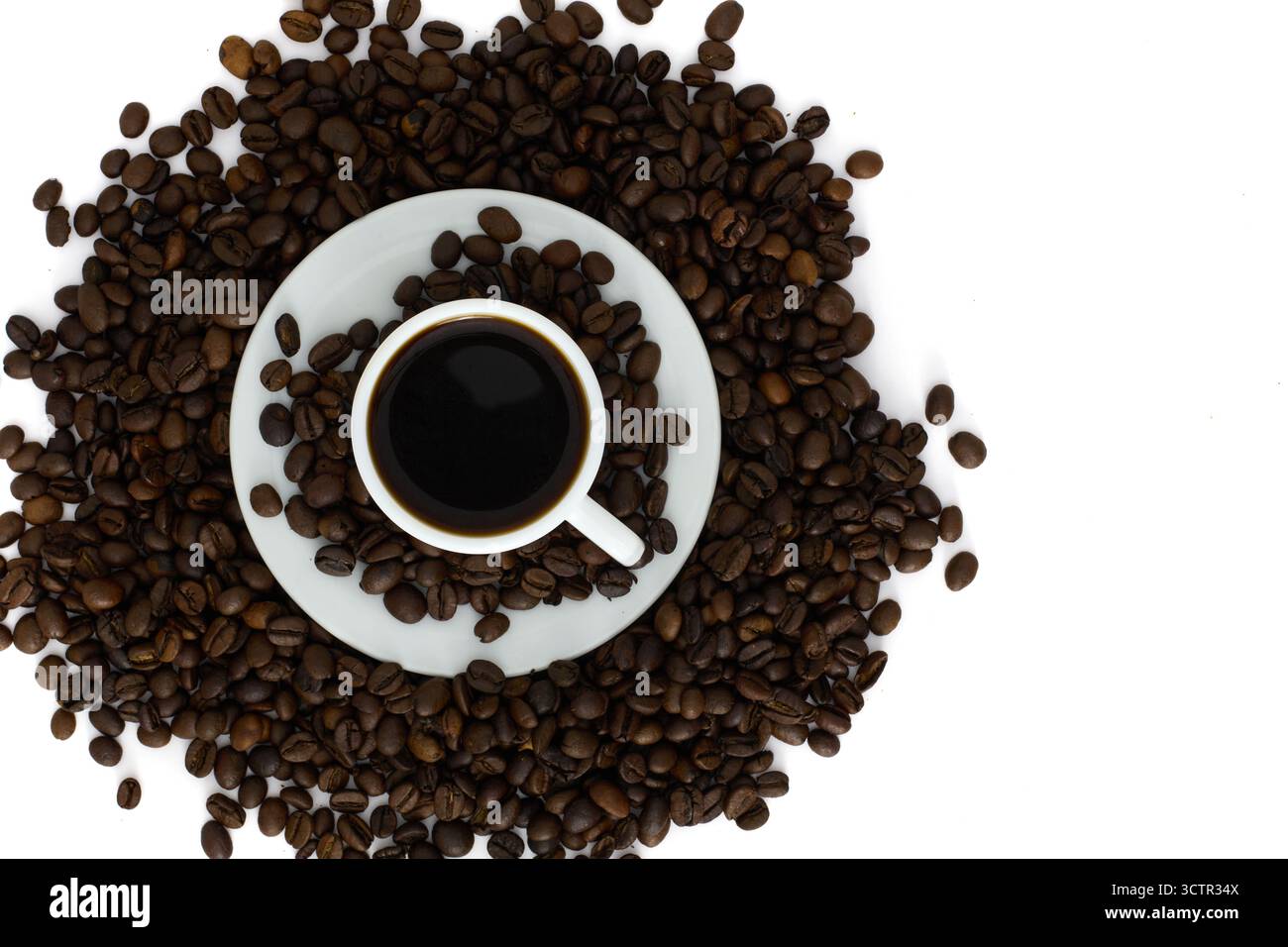 Tazza di caffè nero circondata da chicchi di caffè tostati su sfondo bianco. Vista dall'alto di un espresso fresco. Foto Stock