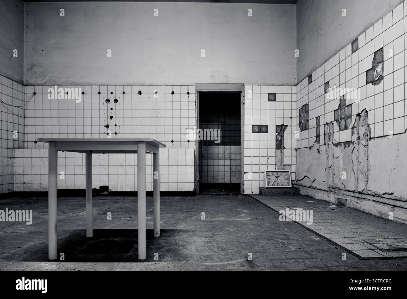 Sala industriale abbandonata con tavolo vecchio e piastrelle rotte - Fotografia in bianco e nero per l'arte del posto perduto Foto Stock