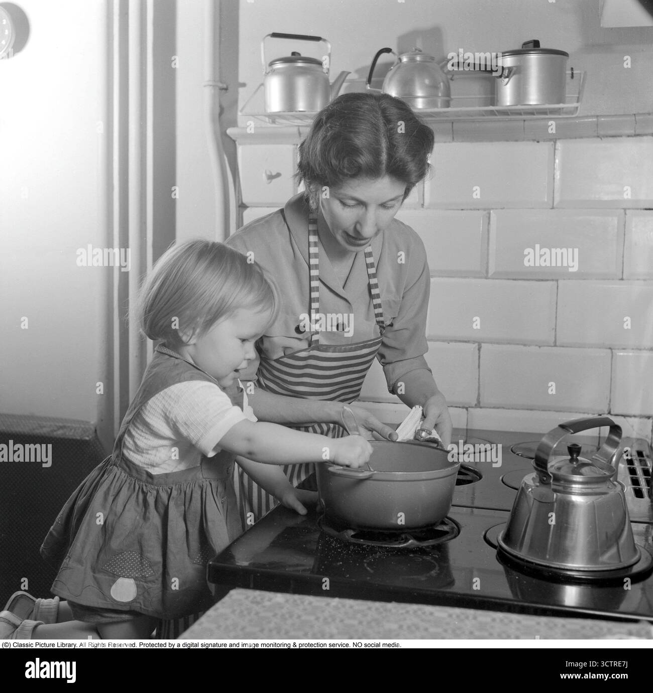 Nel 1956, una madre e una figlia stanno al piano cottura a gas, preparando la cena insieme. Su uno scaffale dietro di loro si trova la classica "Visseljohanna", la caffettiera fischiante. (Rif. Conard 3159) Foto Stock