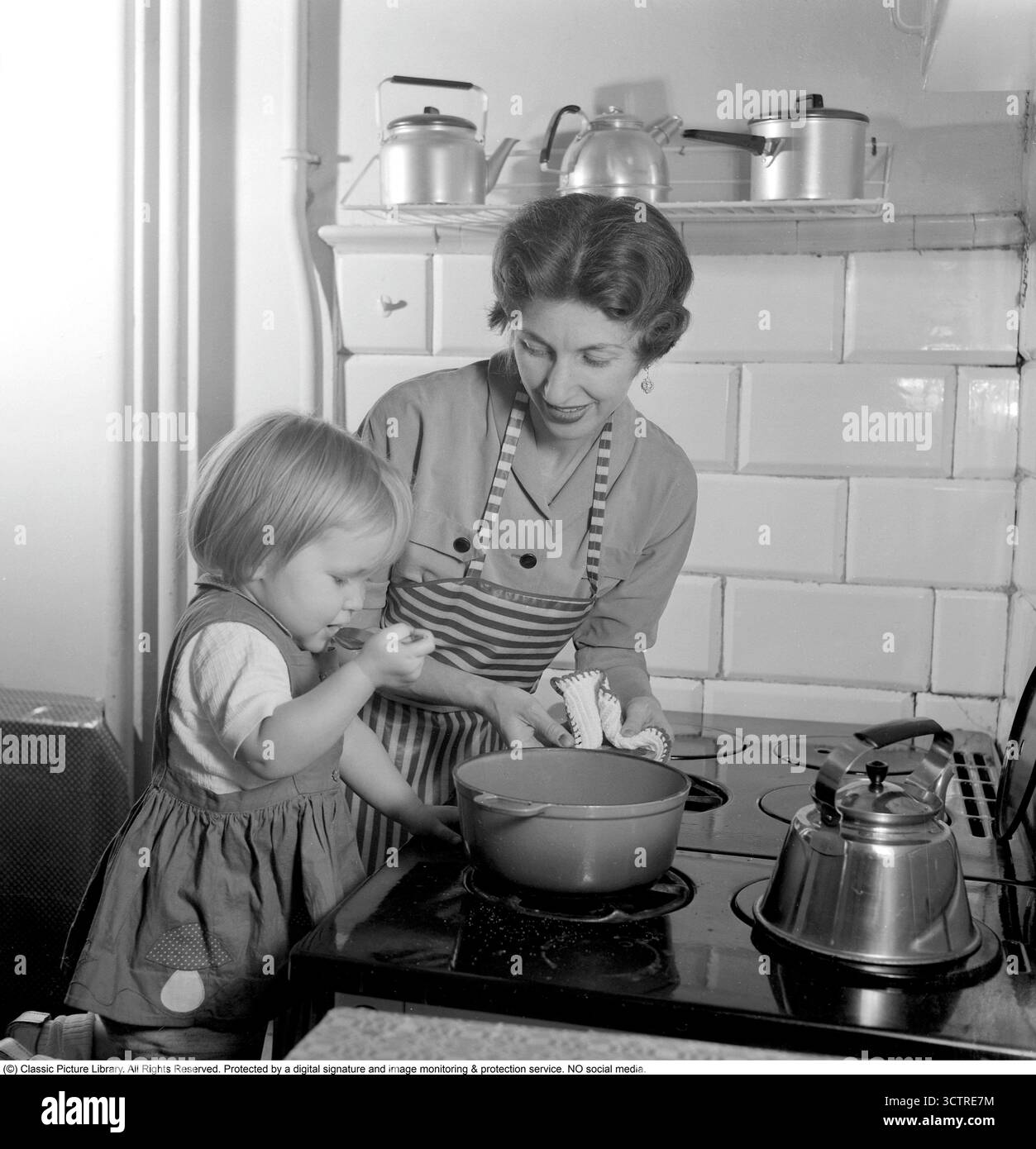 Nel 1956, una madre e una figlia stanno al piano cottura a gas, preparando la cena insieme. Su uno scaffale dietro di loro si trova la classica "Visseljohanna", la caffettiera fischiante. (Rif. Conard 3159) Foto Stock